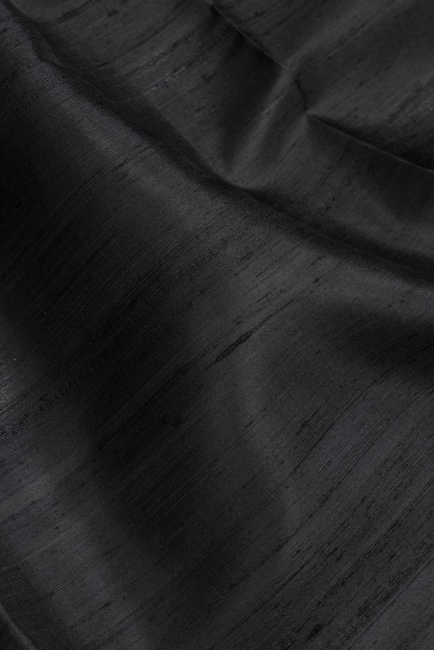 Close up of Black Dual Tone Raw Silk Saree with Plain Body and Zari Border.  displaying folds