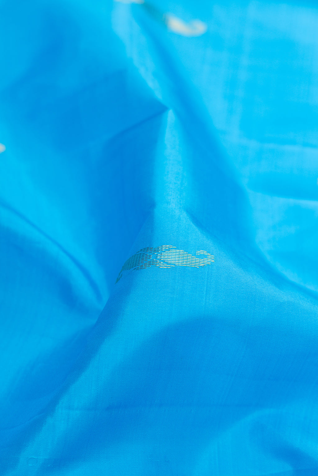 Close up of Sky Blue Kanchipuram Silk Saree with Zari Butta on the body and Fancy Border.  displaying folds