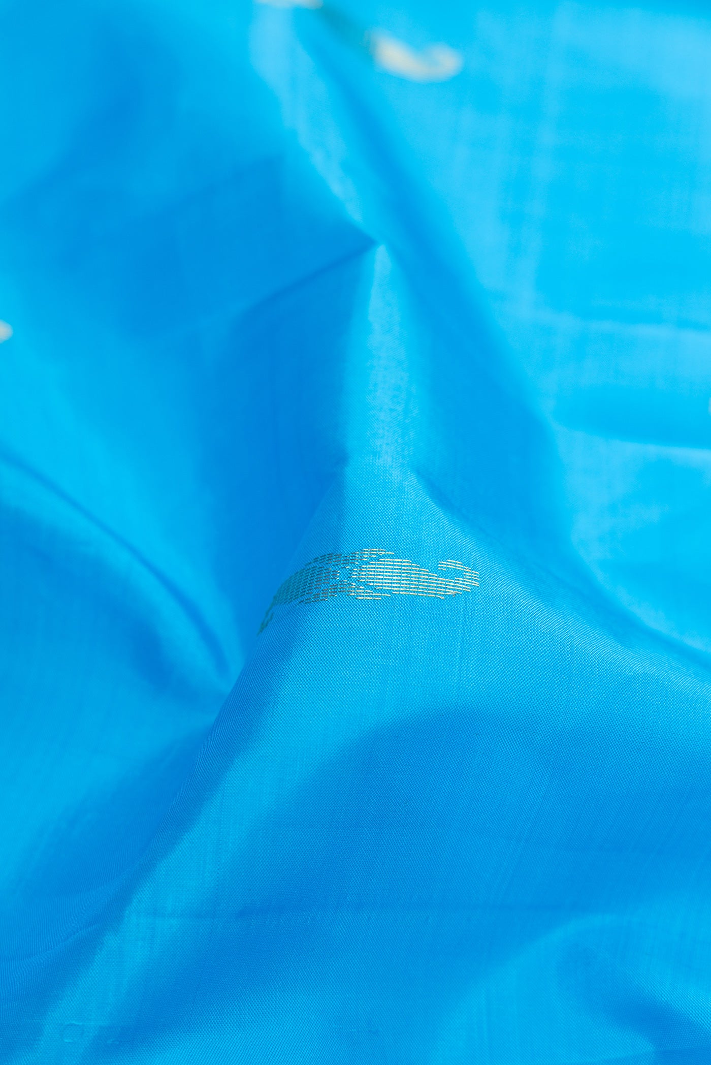 Close up of Sky Blue Kanchipuram Silk Saree with Zari Butta on the body and Fancy Border.  displaying folds