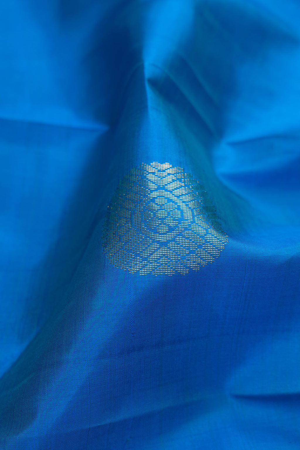 Close up of Peacock Blue Kanchipuram Silk Saree with Zari Butta on the body and Zari Border.  displaying folds