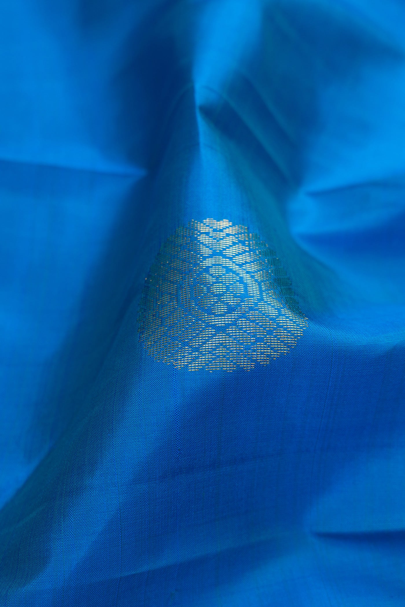 Close up of Peacock Blue Kanchipuram Silk Saree with Zari Butta on the body and Zari Border.  displaying folds