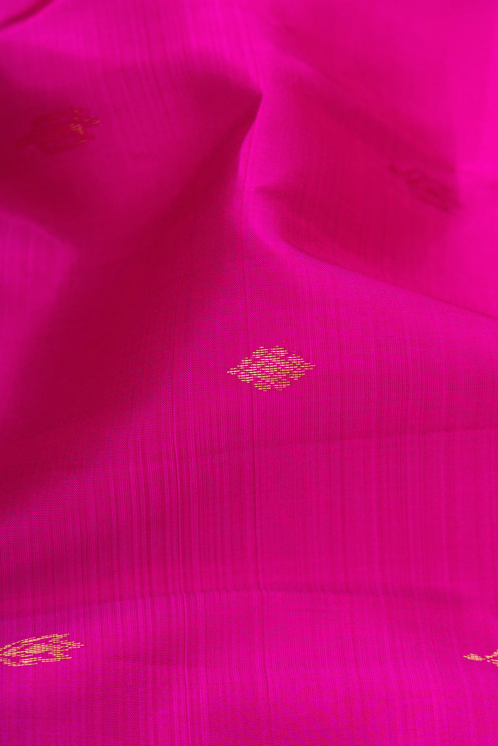 Close up of Magenta Kanchipuram Silk Saree with Zari Butta on the body and Zari Border.  displaying folds