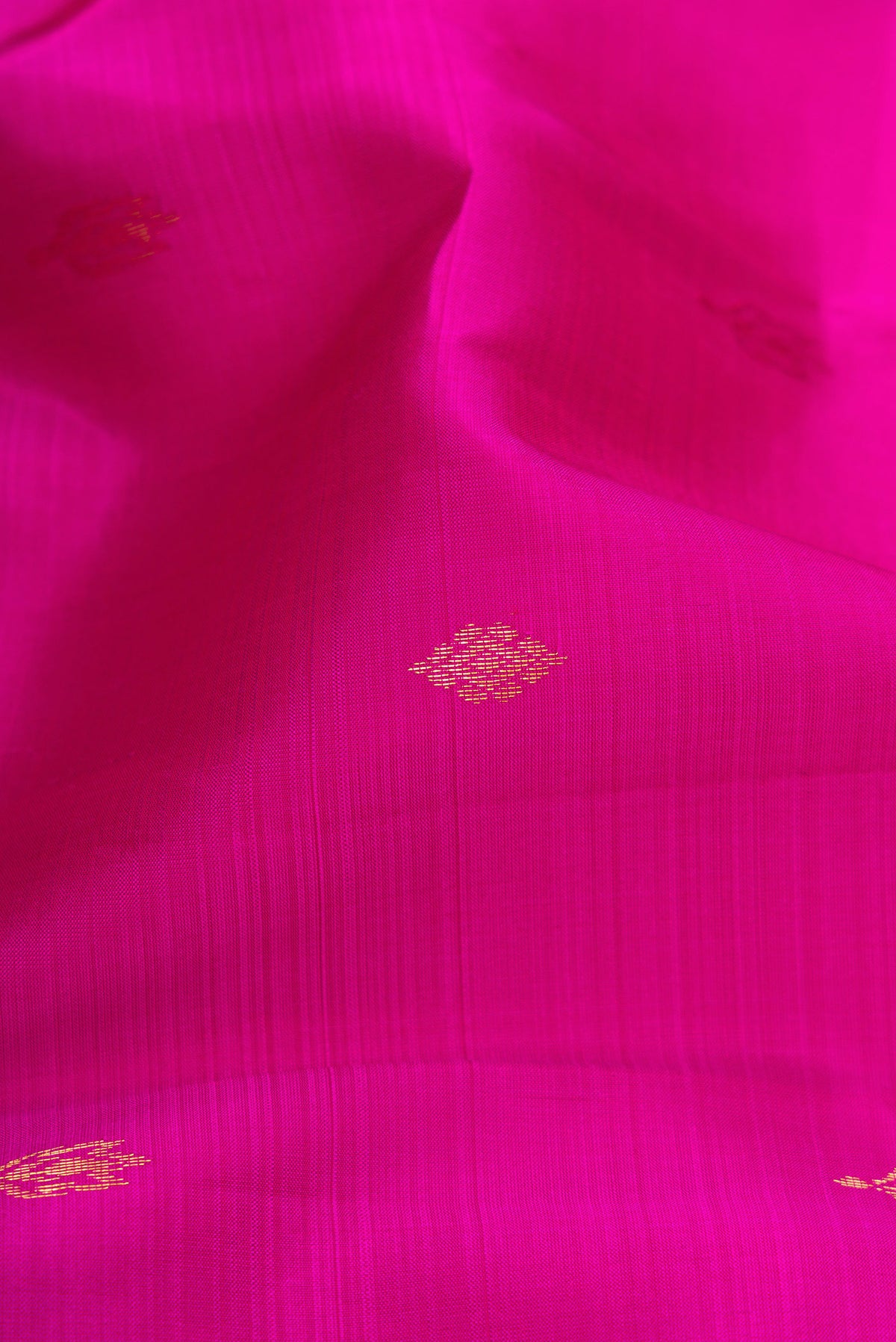 Close up of Magenta Kanchipuram Silk Saree with Zari Butta on the body and Zari Border.  displaying folds