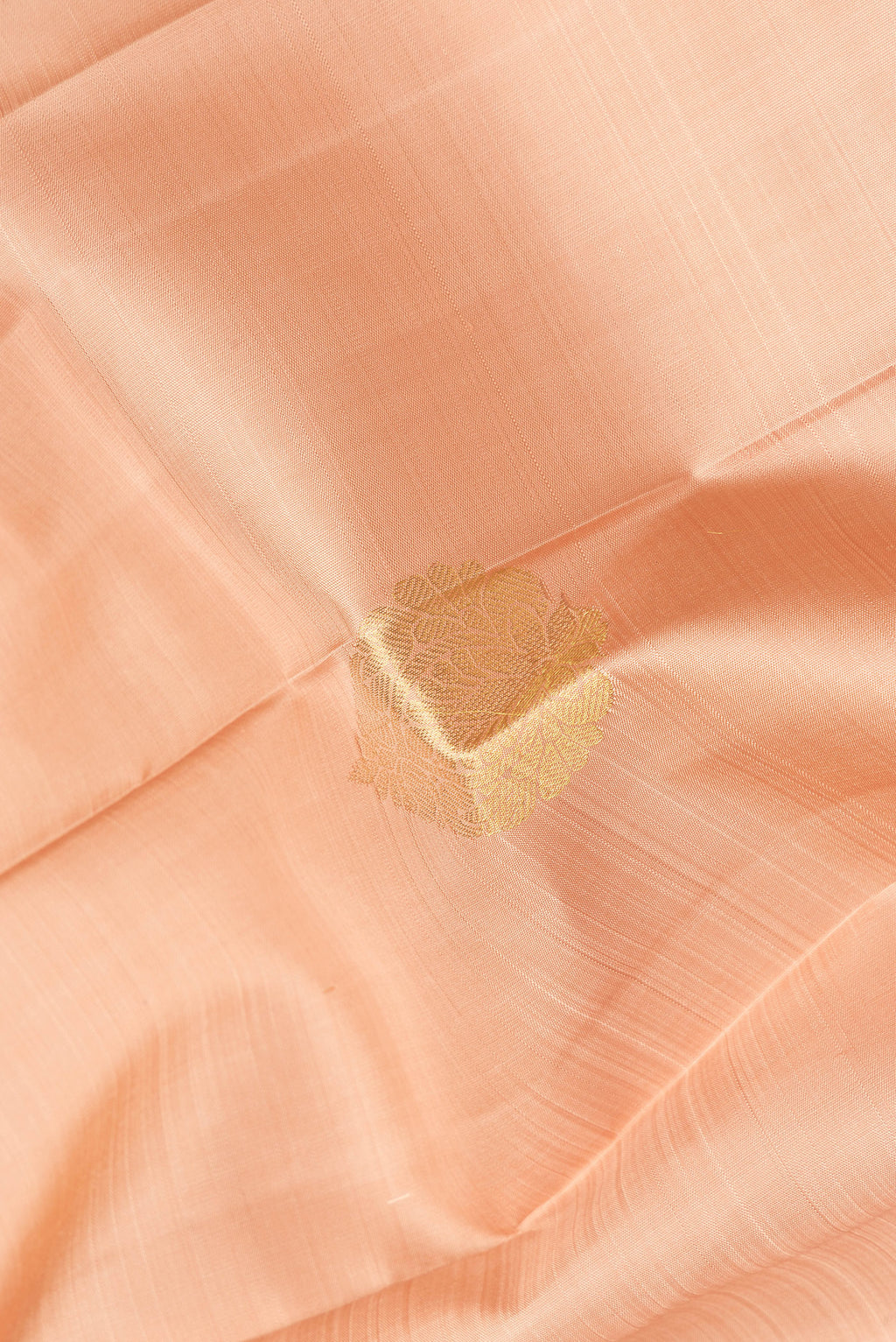 Close up of Golden Peach Dual Tone Kanjivaram Silk Saree with Zari Butta on the body and Zari Border.  displaying folds