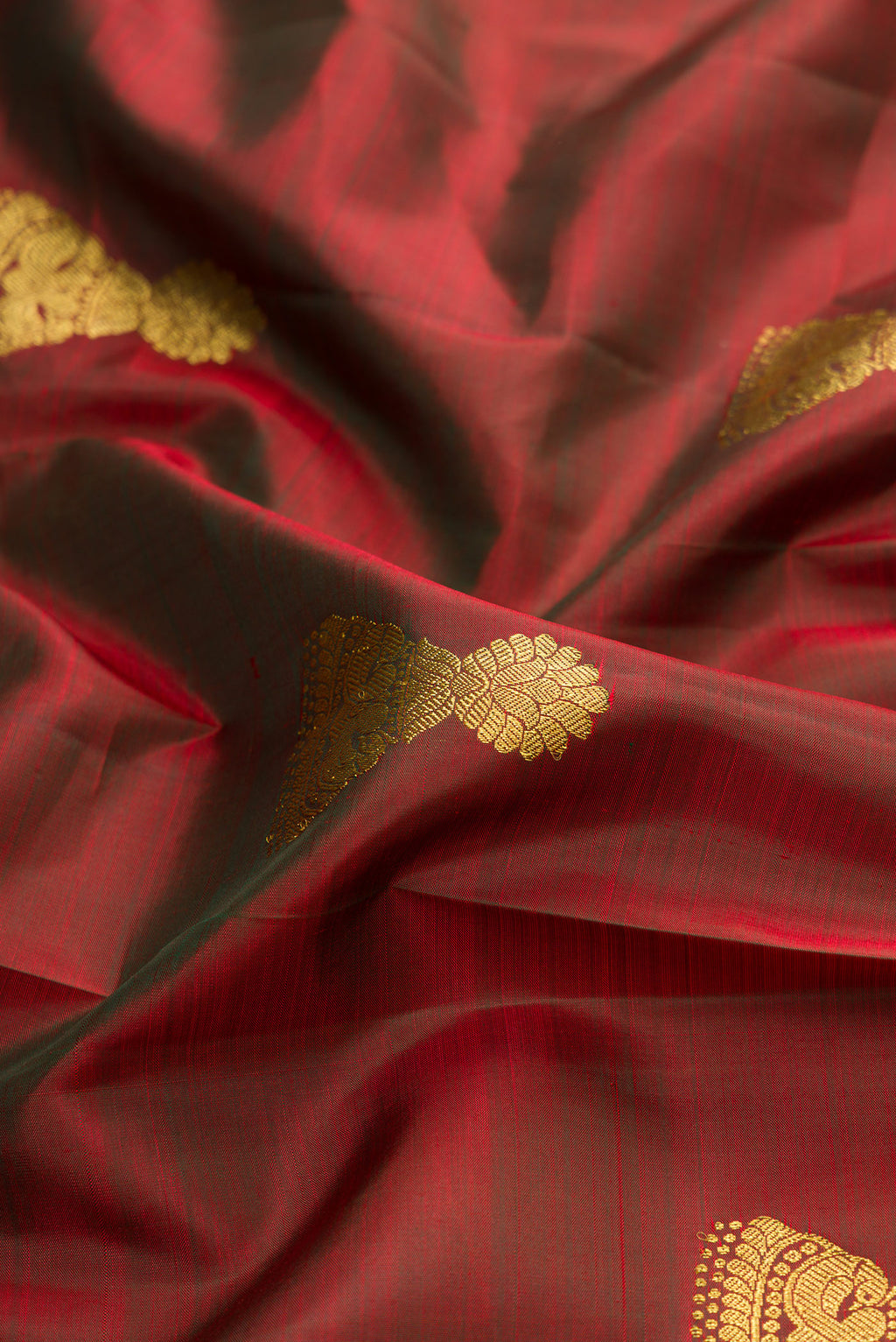 Close up of Maroon Dual Tone Kanjivaram Silk Saree with Zari Butta on the body and Zari Border.  displaying folds