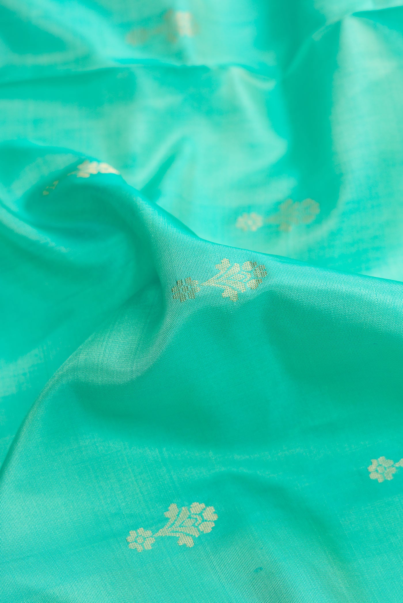 Close up of Green Dual Tone Soft Silk Saree with Zari Butta on the body and Zari Border.  displaying folds