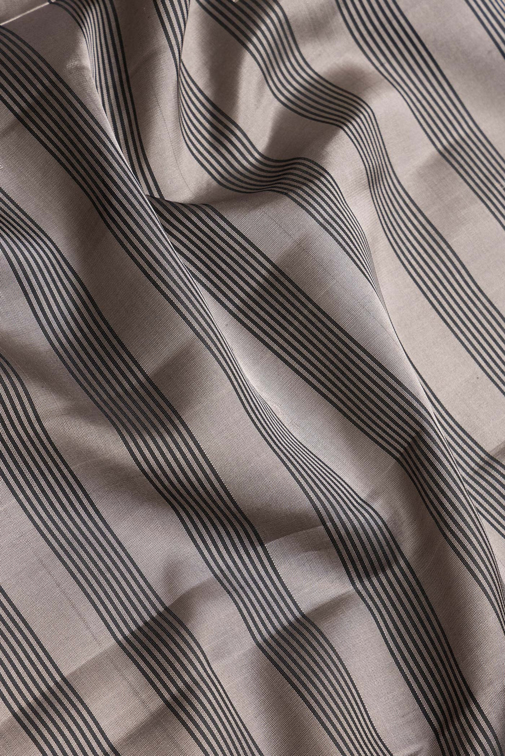 Close up of Grey Dual Tone Soft Silk Saree with Stripes on the body and Zari Border.  displaying folds