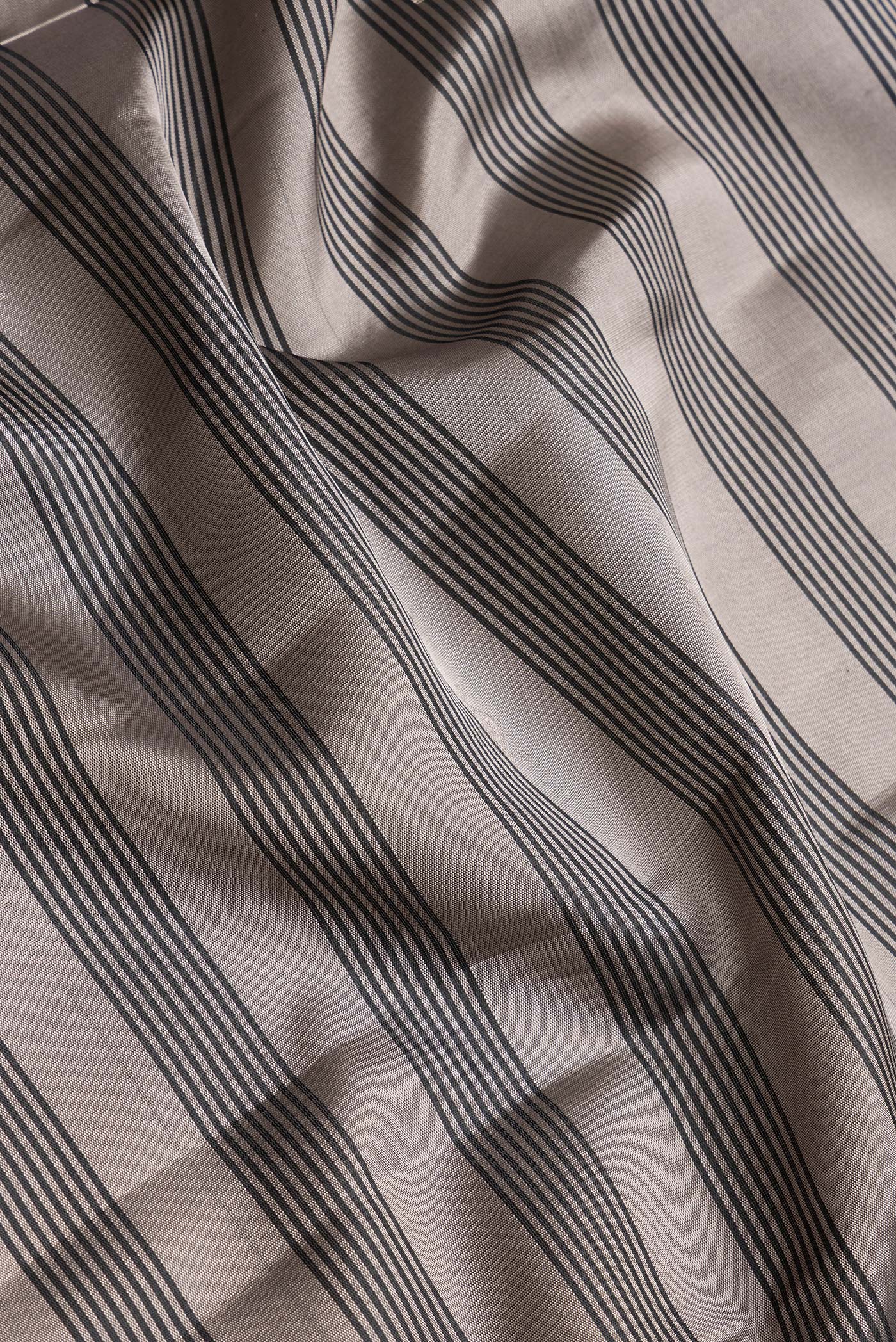Close up of Grey Dual Tone Soft Silk Saree with Stripes on the body and Zari Border.  displaying folds