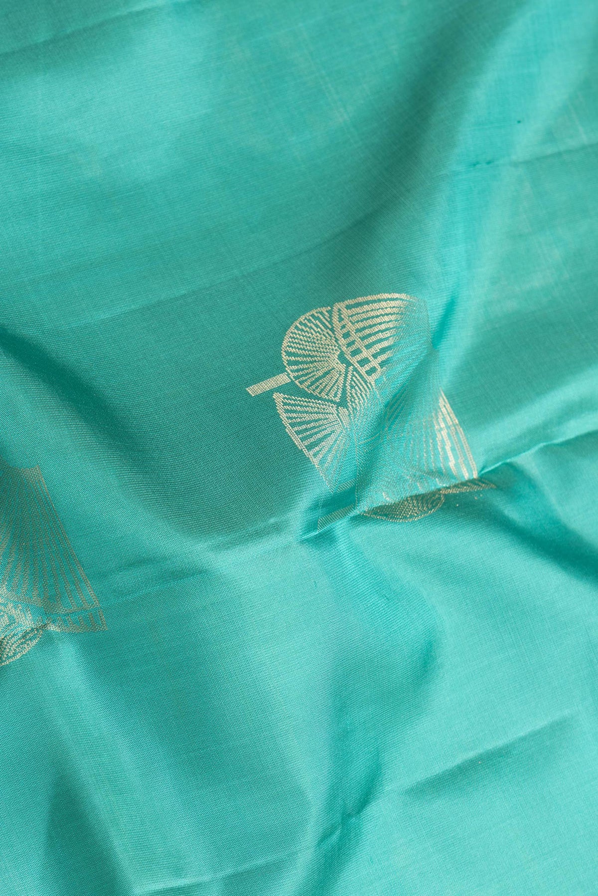 Close up of Sea Green Dual Tone Soft Silk Saree with Zari Butta on the body and Without Border.  displaying folds