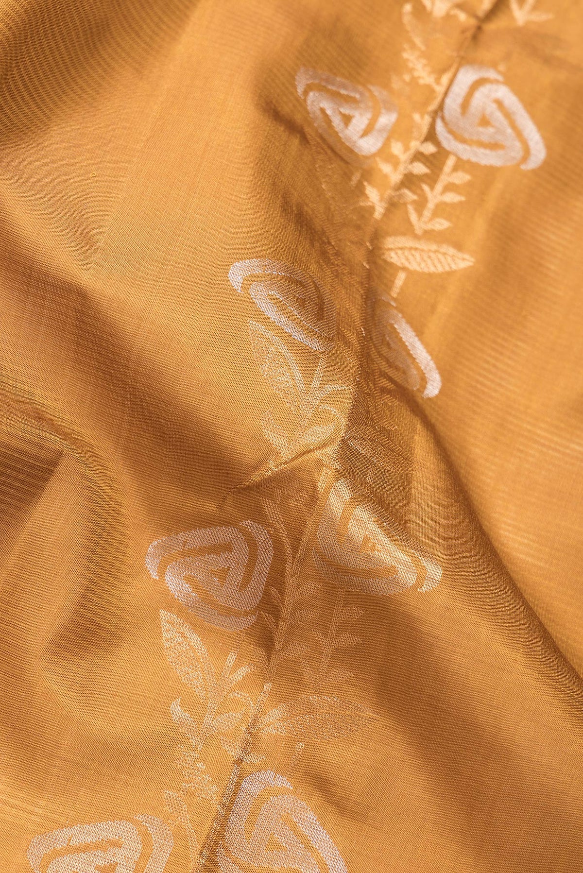 Close up of Mustard Dual Tone Soft Silk Saree with Zari Butta on the body and Zari Border.  displaying folds