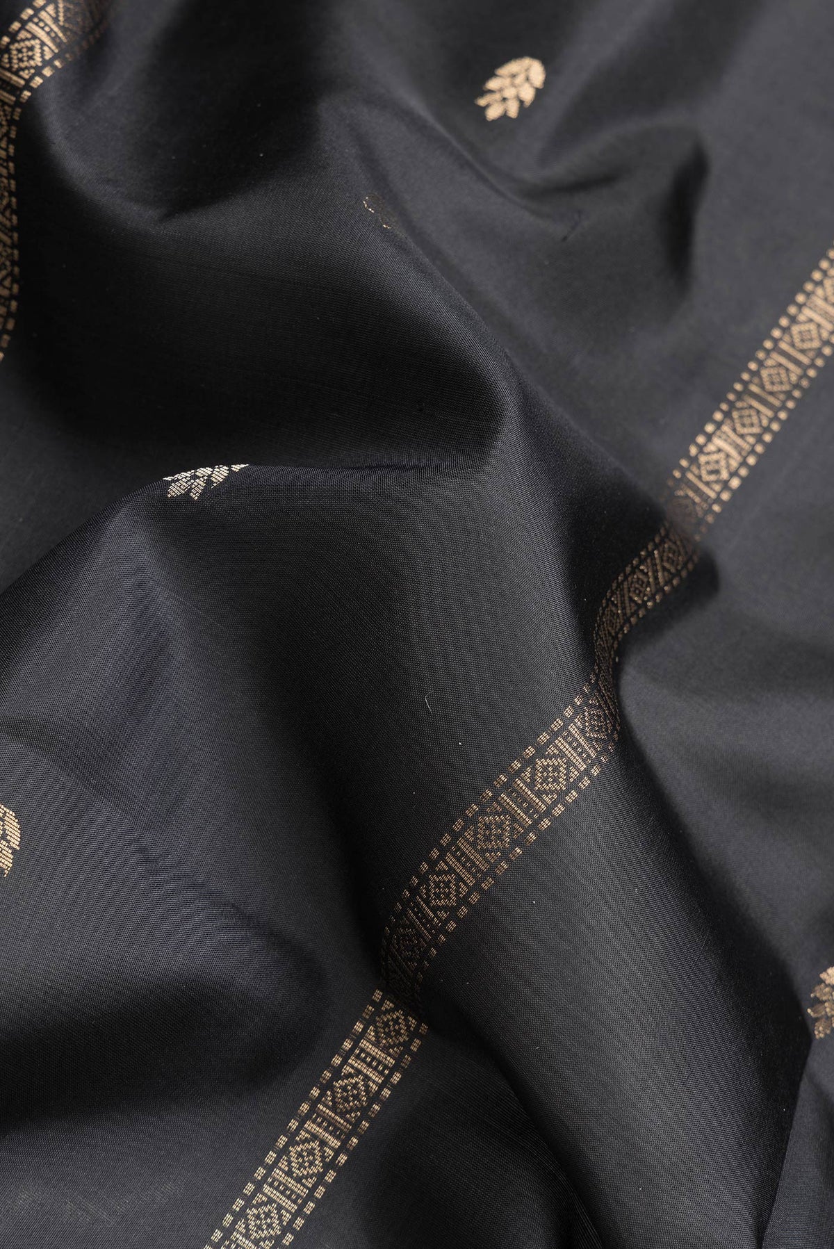 Close up of Black Dual Tone Soft Silk Saree with Zari Butta on the body and Zari Border.  displaying folds