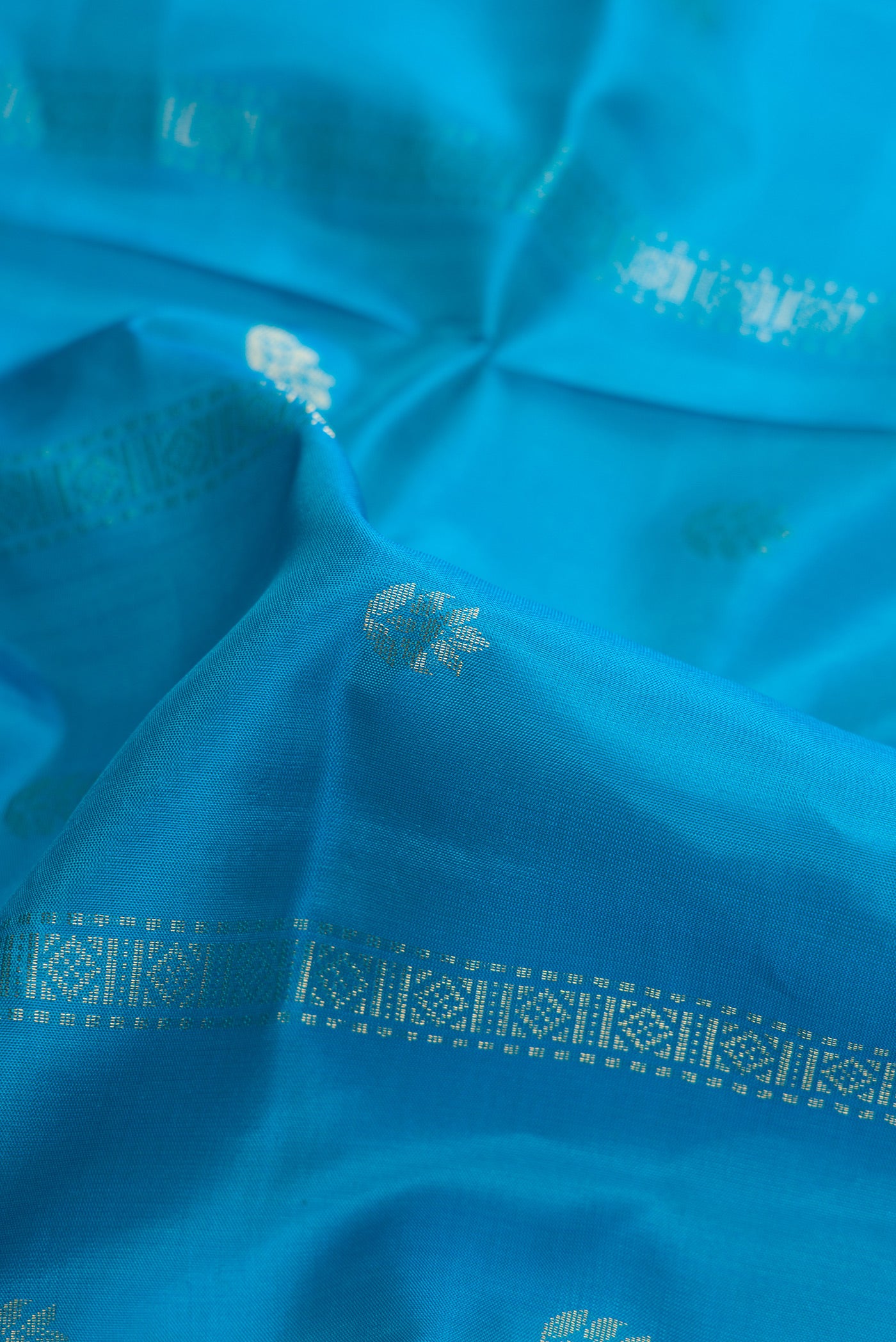 Close up of Sky Blue Dual Tone Soft Silk Saree with Zari Butta on the body and Zari Border.  displaying folds