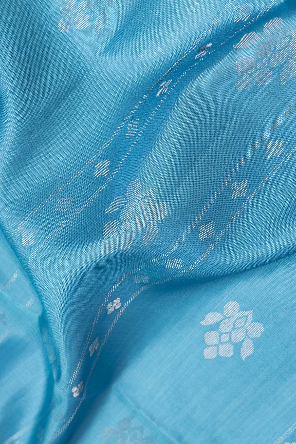 Close up of Sky Blue Dual Tone Soft Silk Saree with Zari Butta on the body and Zari Border.  displaying folds