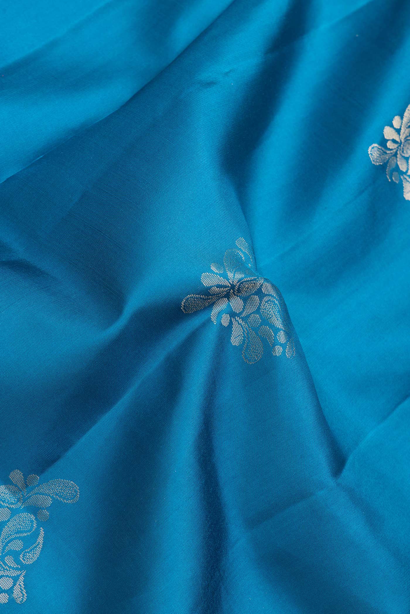 Close up of Peacock Blue Dual Tone Soft Silk Saree with Zari Butta on the body and Zari Border.  displaying folds