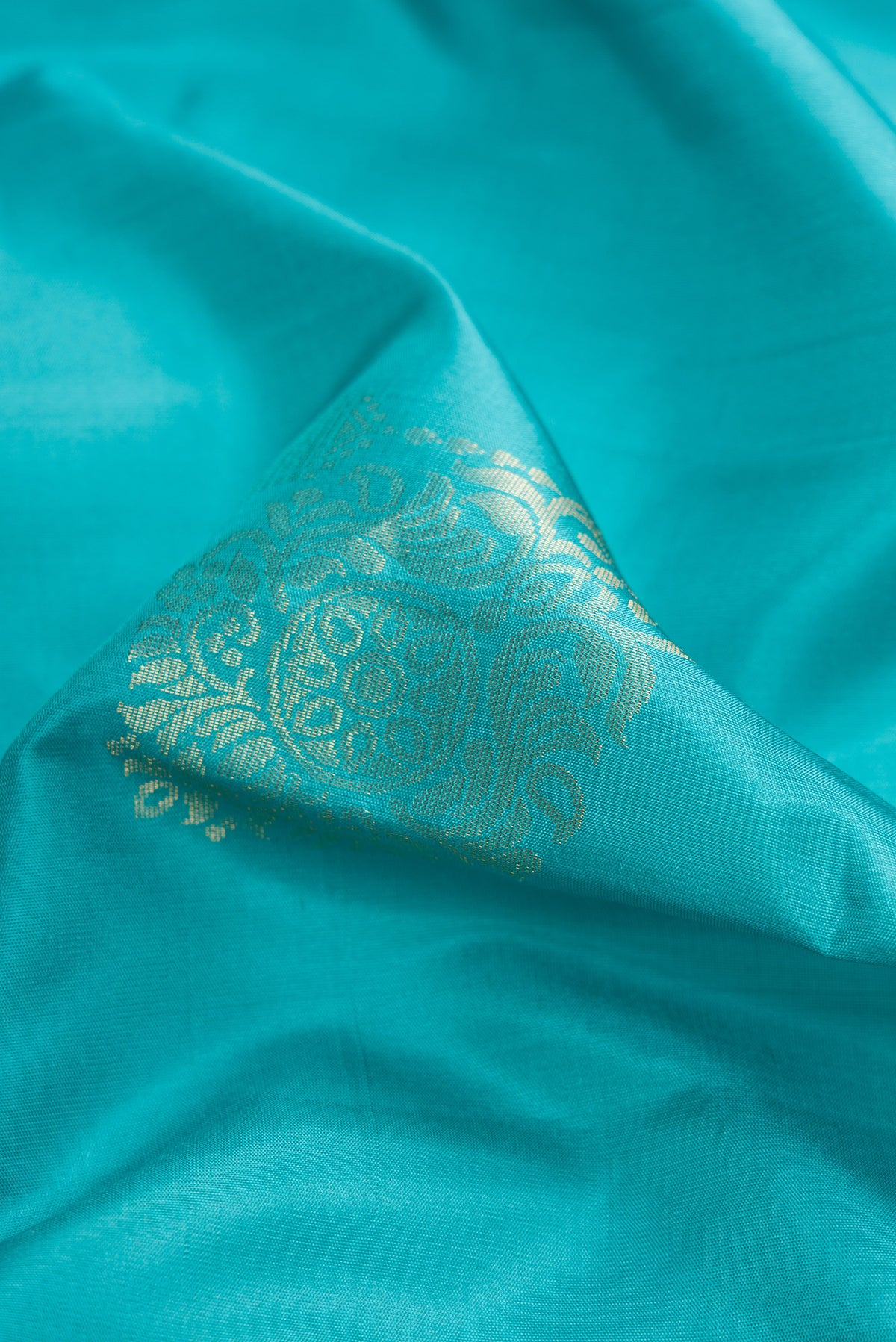 Close up of Light Blue Dual Tone Soft Silk Saree with Zari Butta on the body and Zari Border.  displaying folds