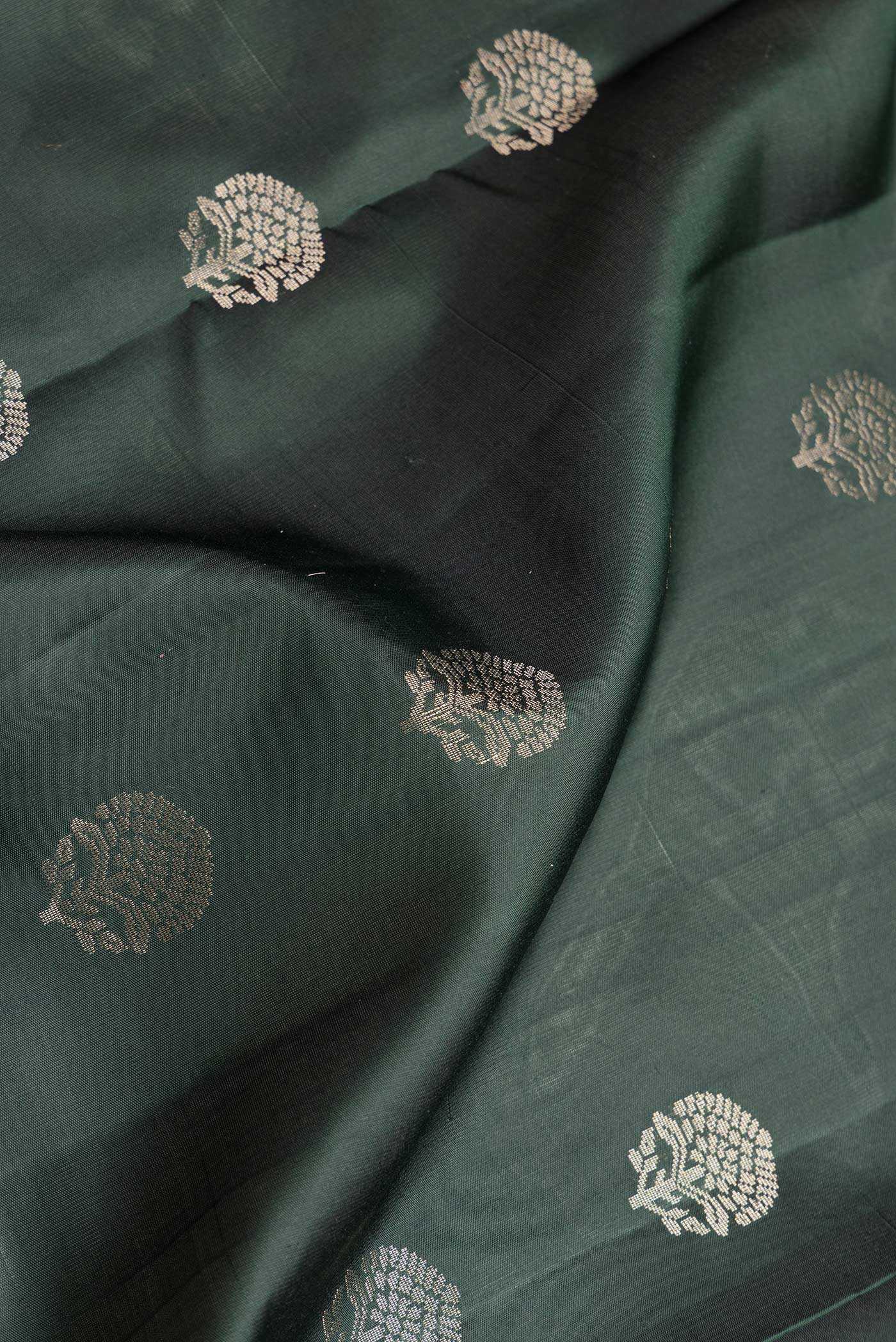 Close up of Bottle Green Dual Tone Soft Silk Saree with Zari Butta on the body and Zari Border.  displaying folds