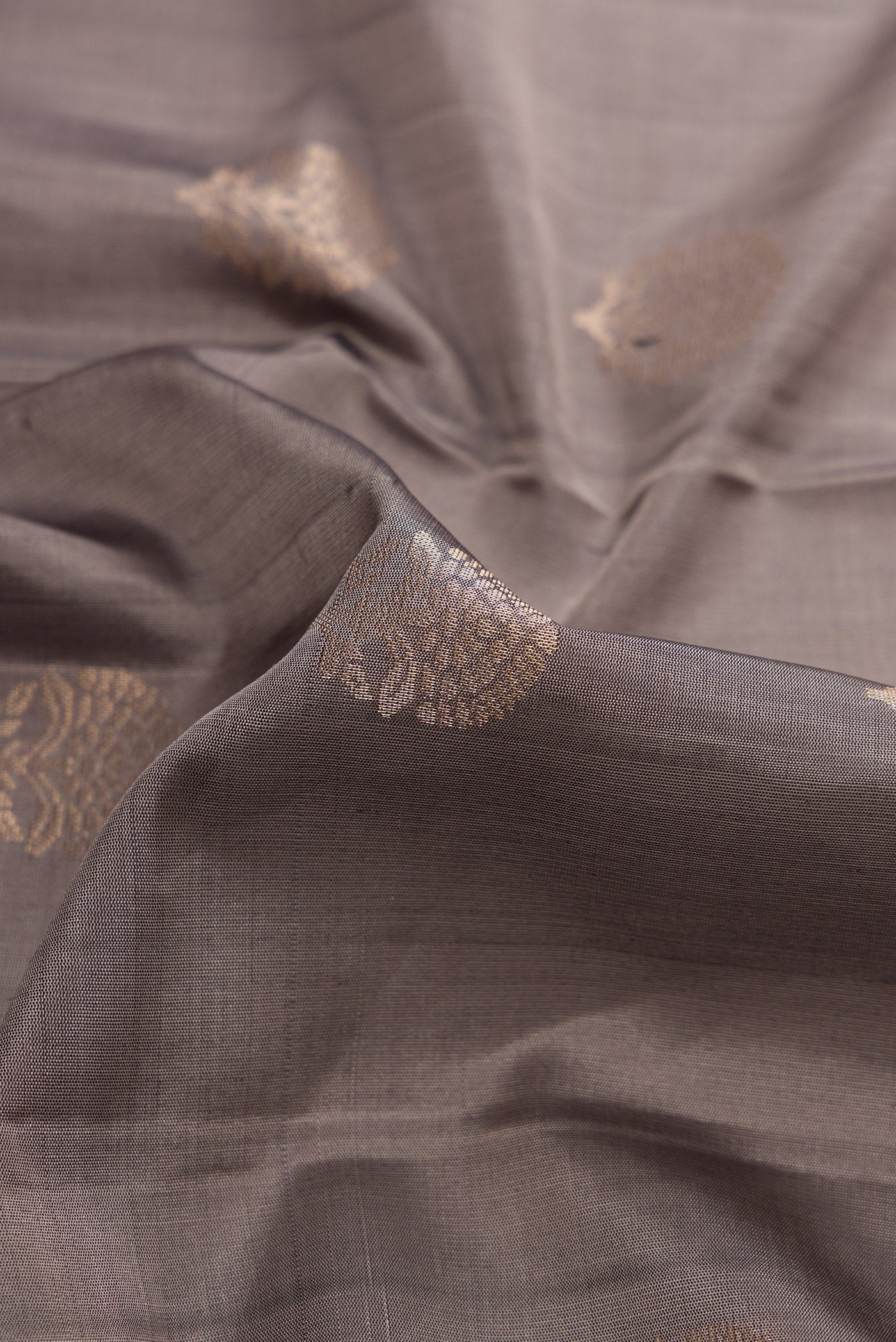Close up of Grey Dual Tone Soft Silk Saree with Zari Butta on the body and Zari Border.  displaying folds