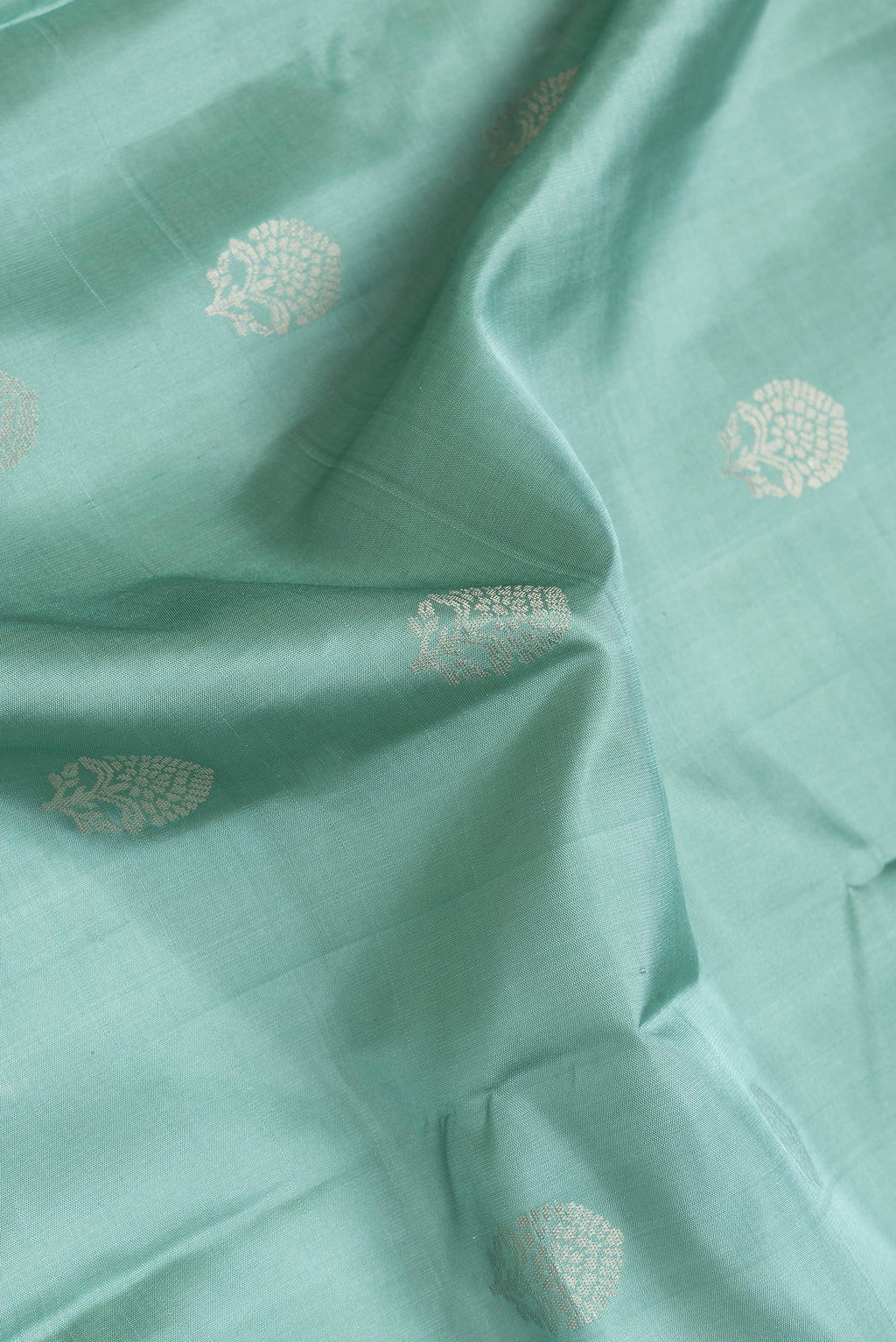 Close up of Sea Green Dual Tone Soft Silk Saree with Zari Butta on the body and Zari Border.  displaying folds