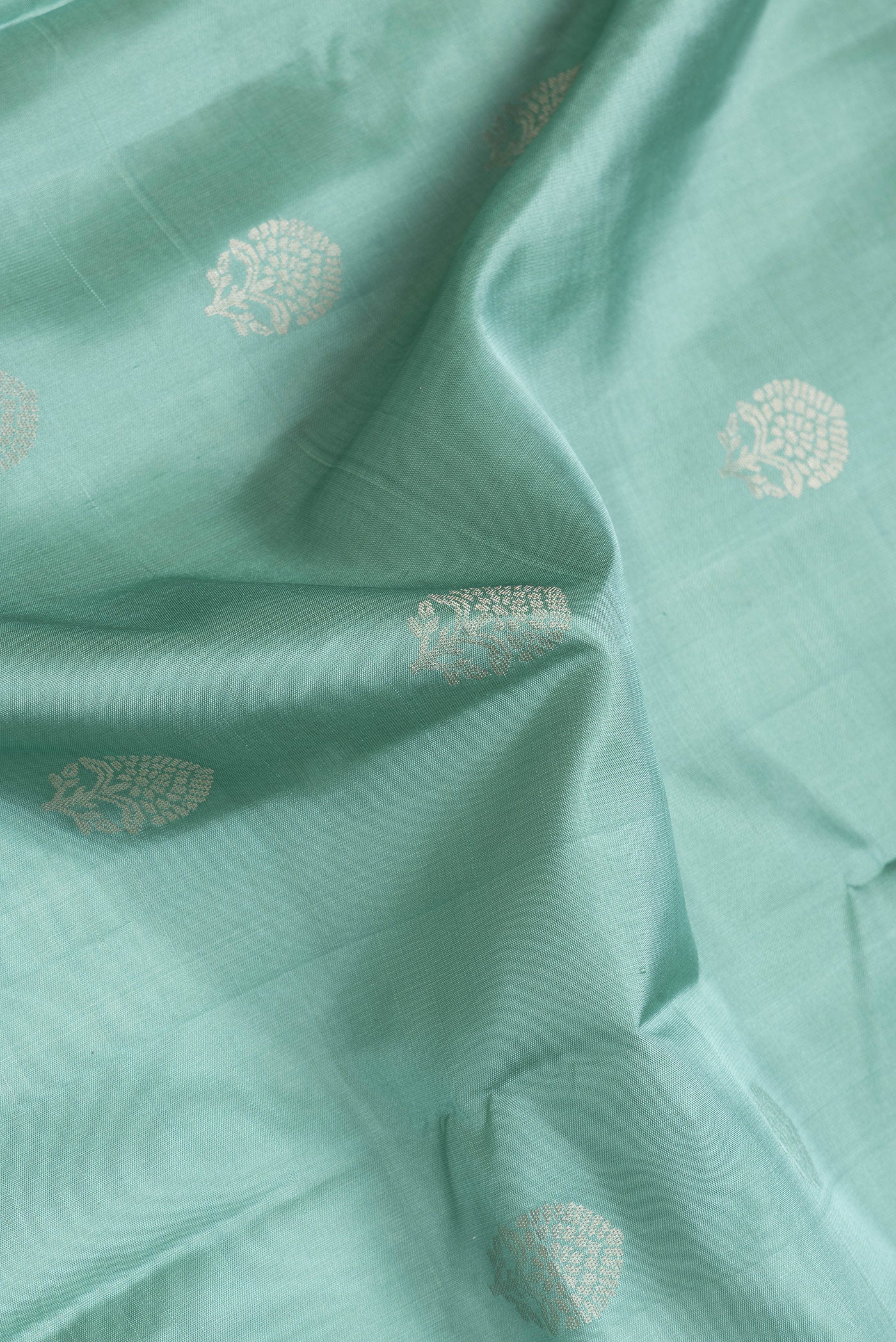 Close up of Sea Green Dual Tone Soft Silk Saree with Zari Butta on the body and Zari Border.  displaying folds