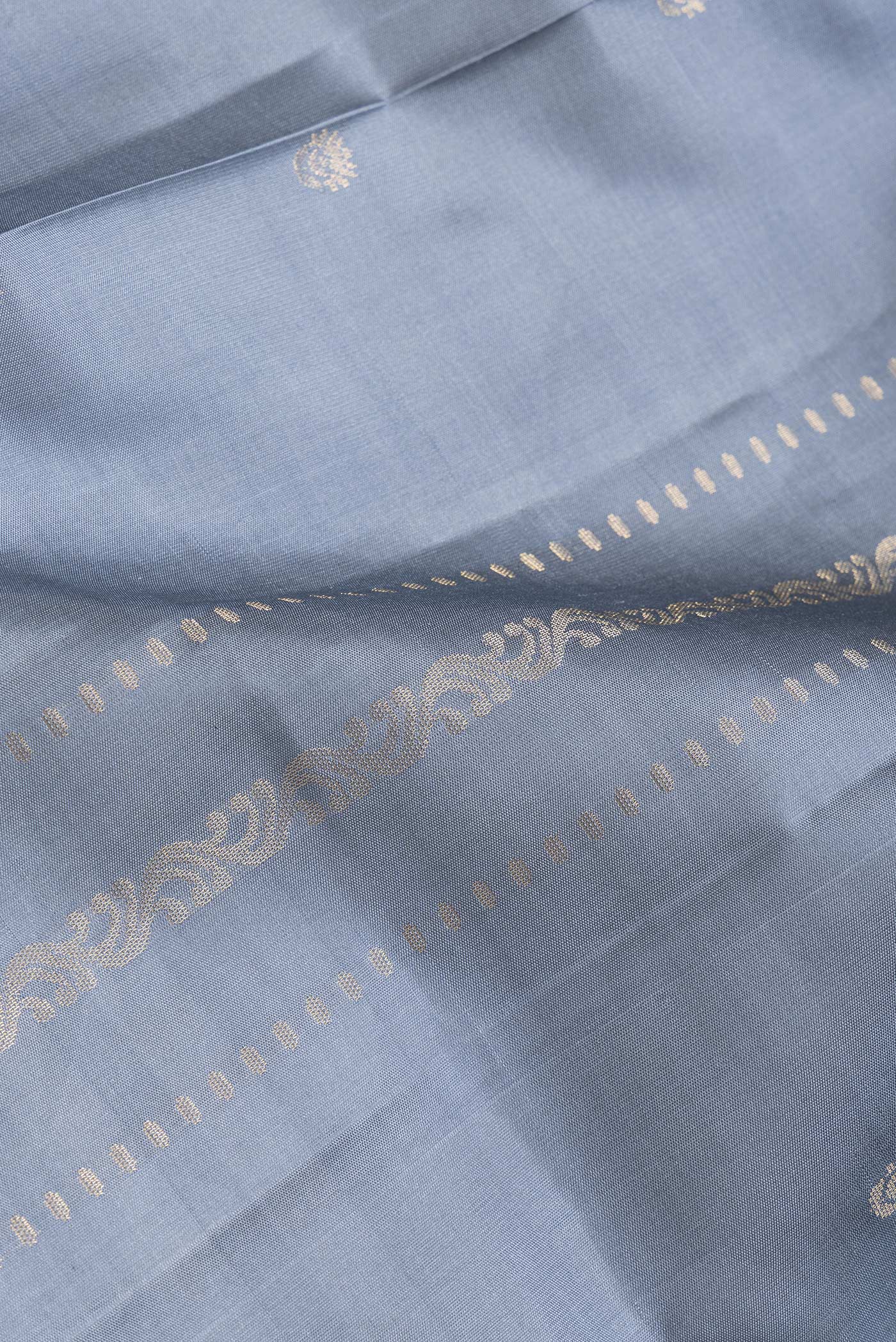 Close up of Grey Dual Tone Soft Silk Saree with Zari Butta on the body and Zari Border.  displaying folds