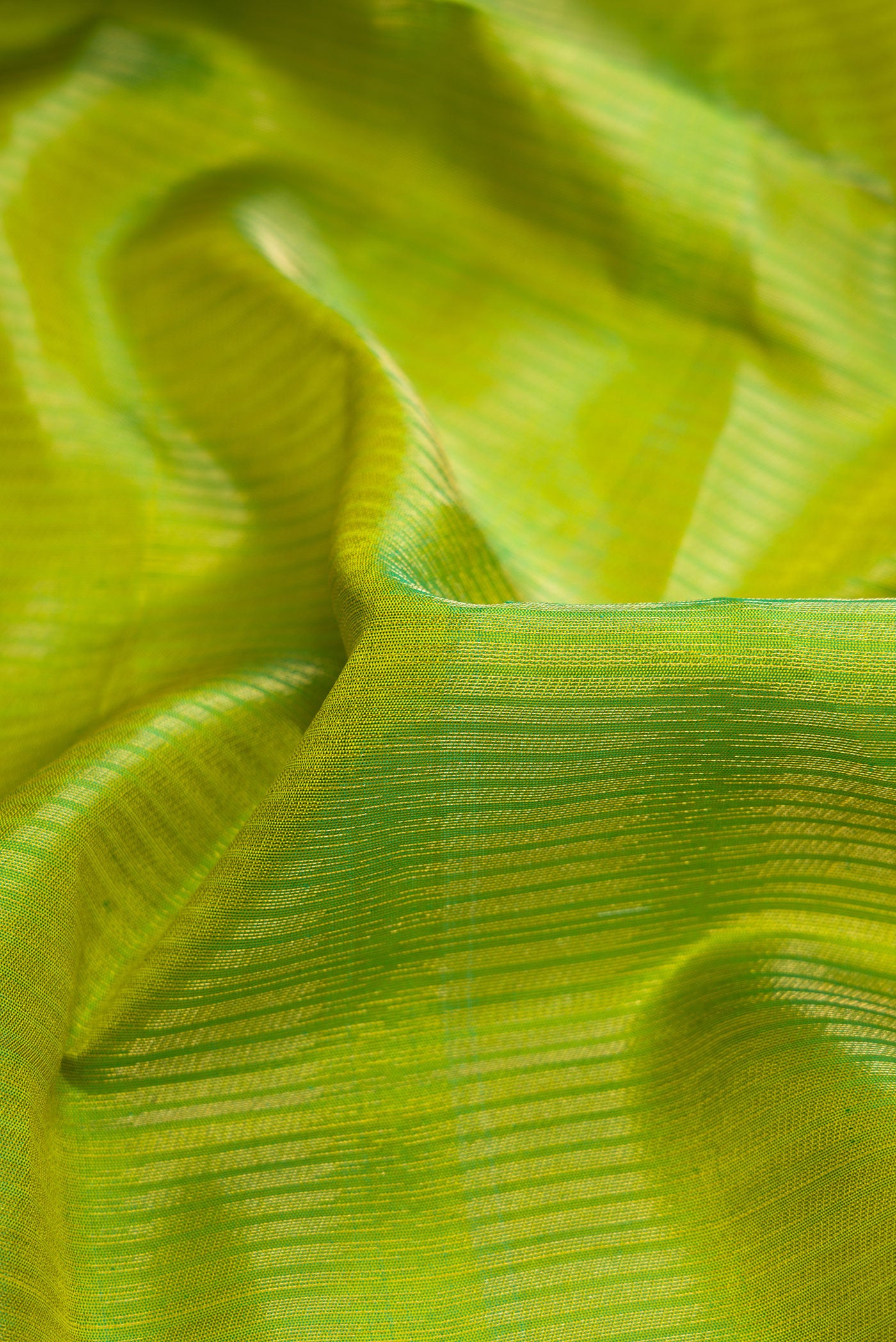 Close up of Green Dual Tone Soft Silk Saree with Zari Brocade on the body and Zari Border.  displaying folds