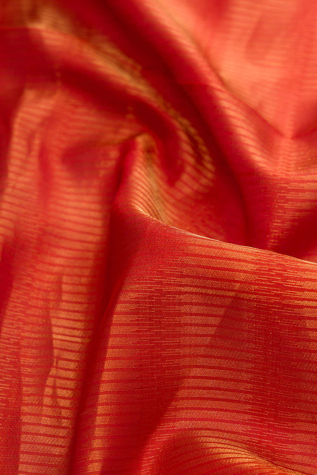 Close up of Brick Orange Dual Tone Soft Silk Saree with Zari Butta on the body and Zari Border.  displaying folds
