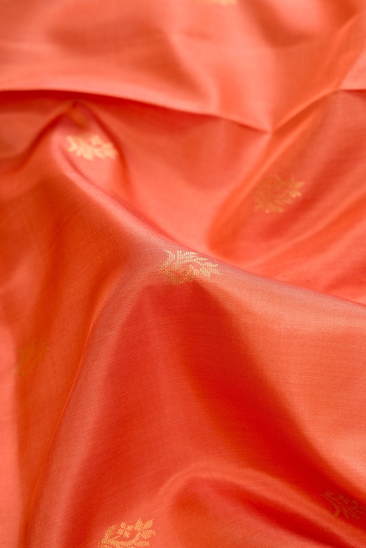 Close up of Golden Peach Dual Tone Soft Silk Saree with Zari Butta on the body and Zari Border.  displaying folds