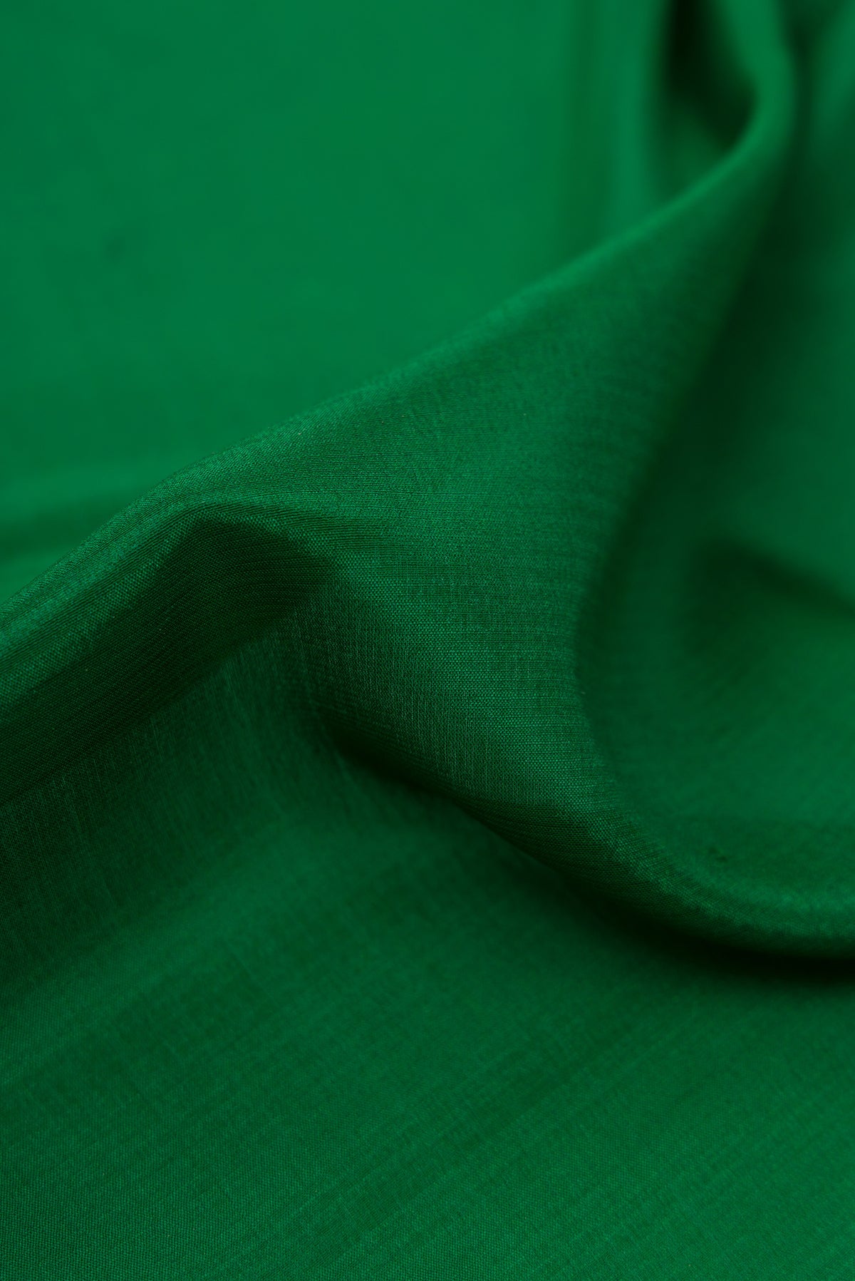 Close up of Bottle Green Mysore Crepe Saree with Plain Body and Zari Border.  displaying folds