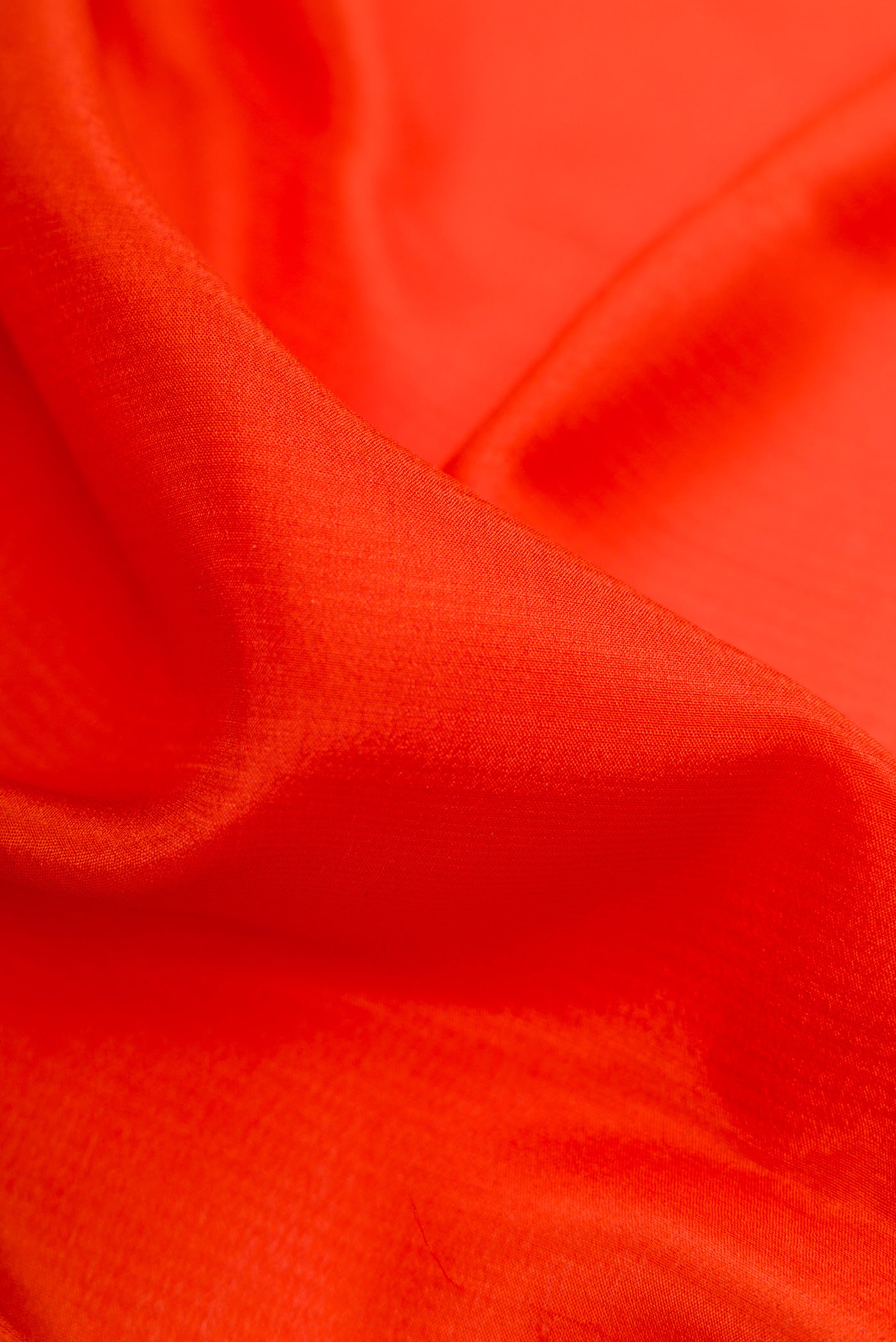 Close up of Orange Mysore Crepe Saree with Plain Body and Zari Border.  displaying folds