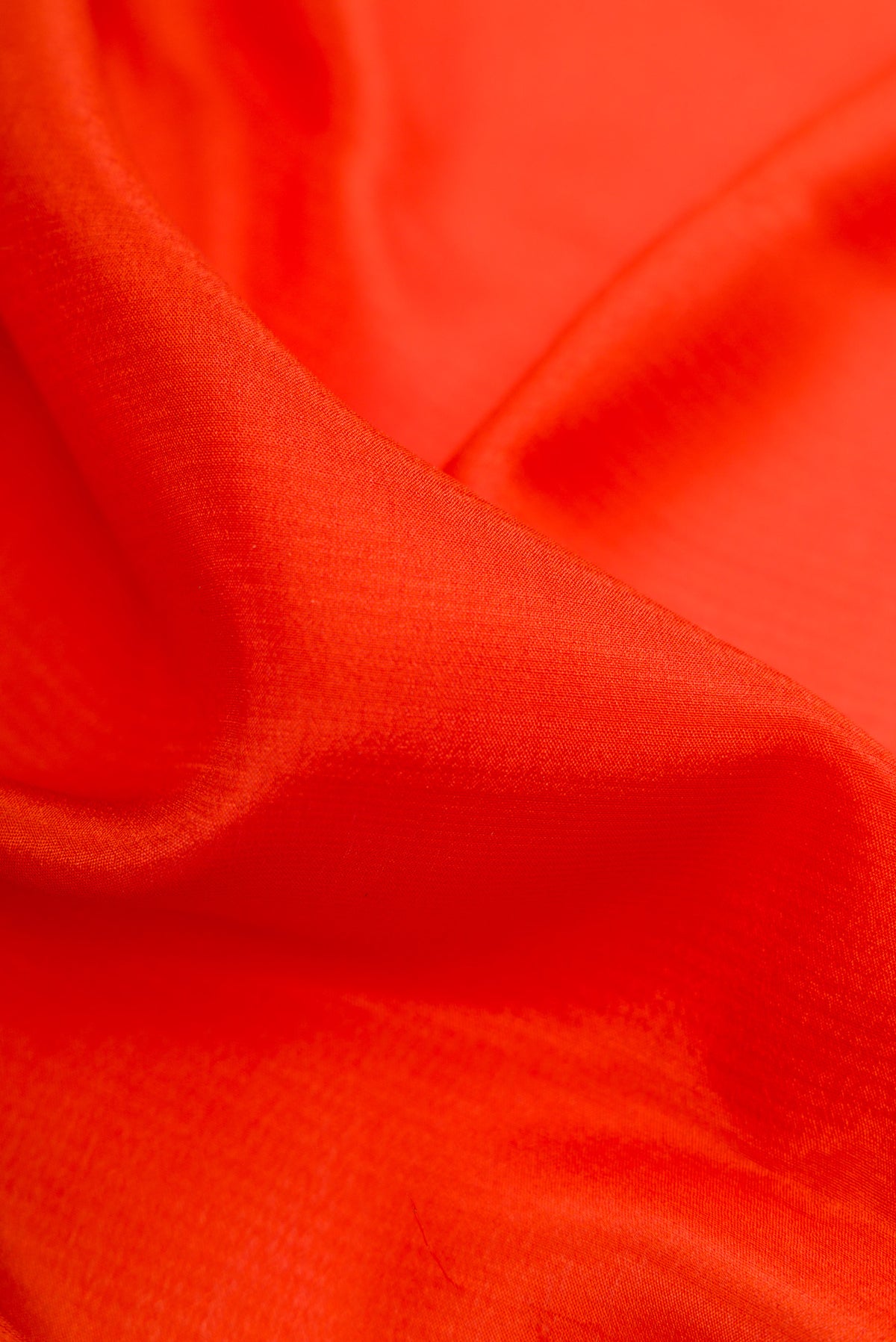 Close up of Orange Mysore Crepe Saree with Plain Body and Zari Border.  displaying folds