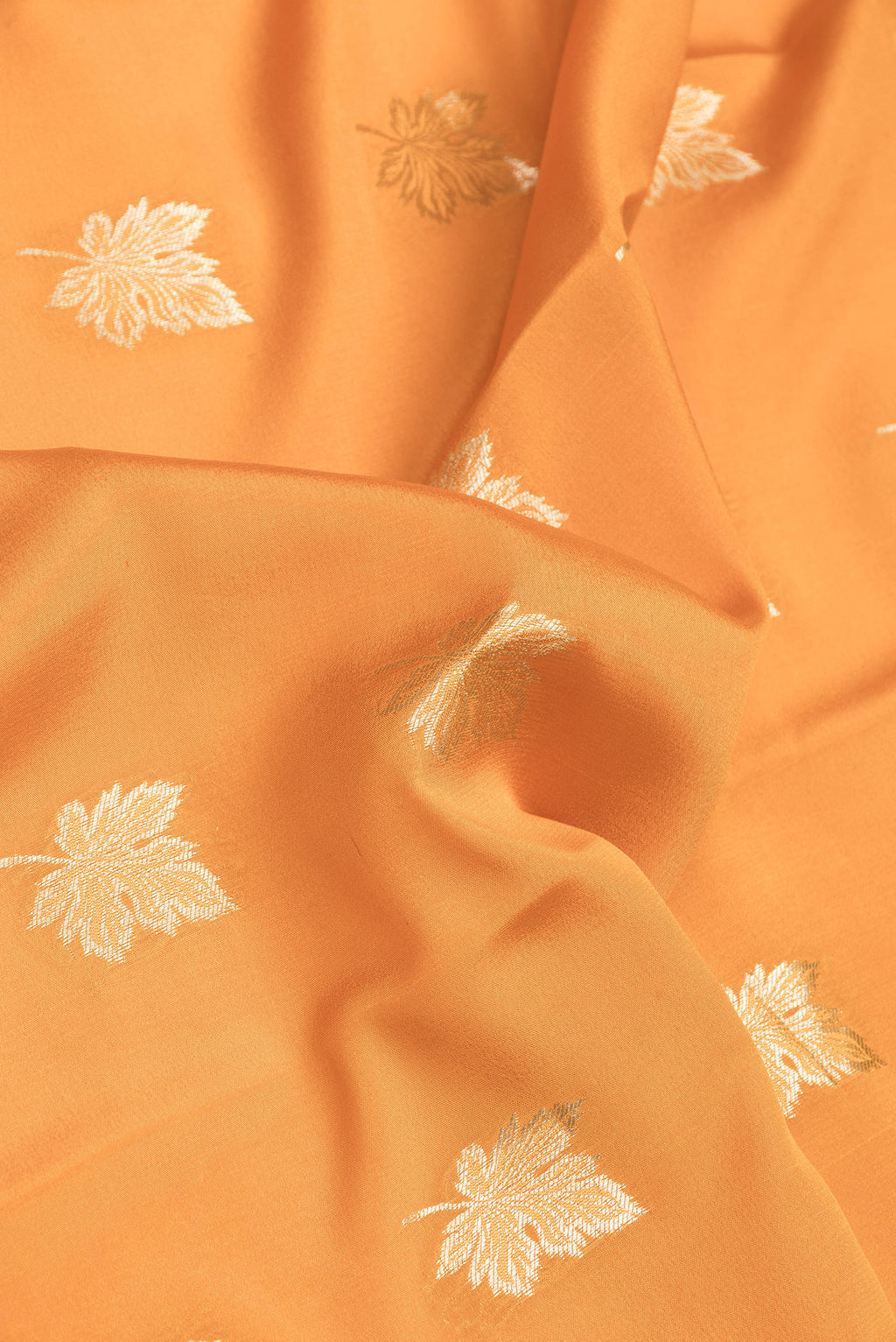 Close up of Orange Dual Tone Mysore Silk Saree with Zari Butta on the body and Zari Border.  displaying folds