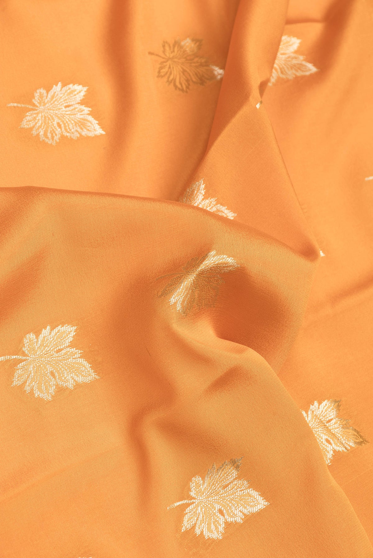 Close up of Orange Dual Tone Mysore Silk Saree with Zari Butta on the body and Zari Border.  displaying folds