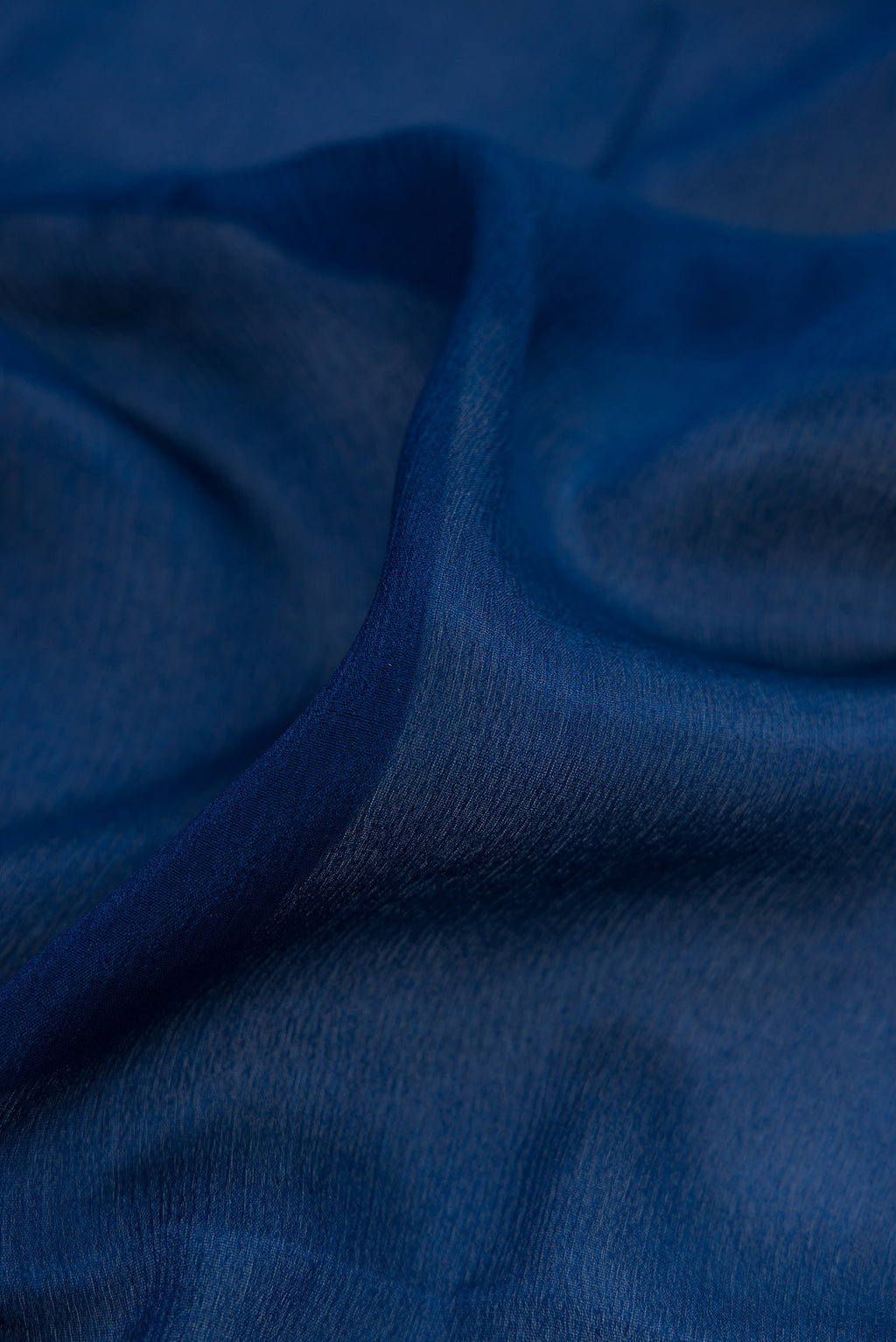 Close up of Blue Georgette Saree with Plain Body and Zari Border.  displaying folds