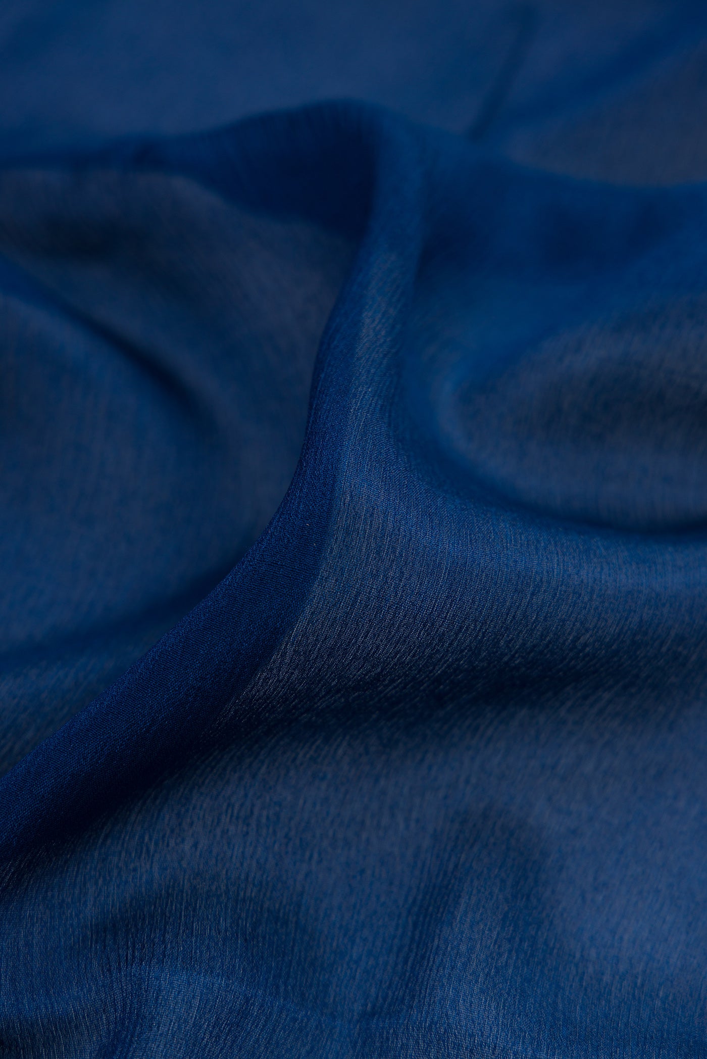 Close up of Blue Georgette Saree with Plain Body and Zari Border.  displaying folds