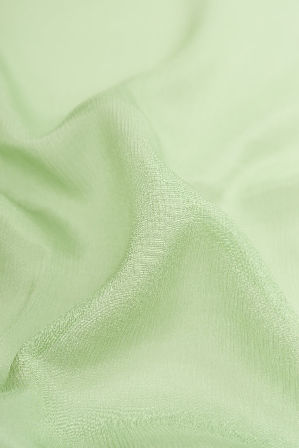 Close up of Pista Green Mysore Chiffon Saree with Plain Body and Zari Border.  displaying folds