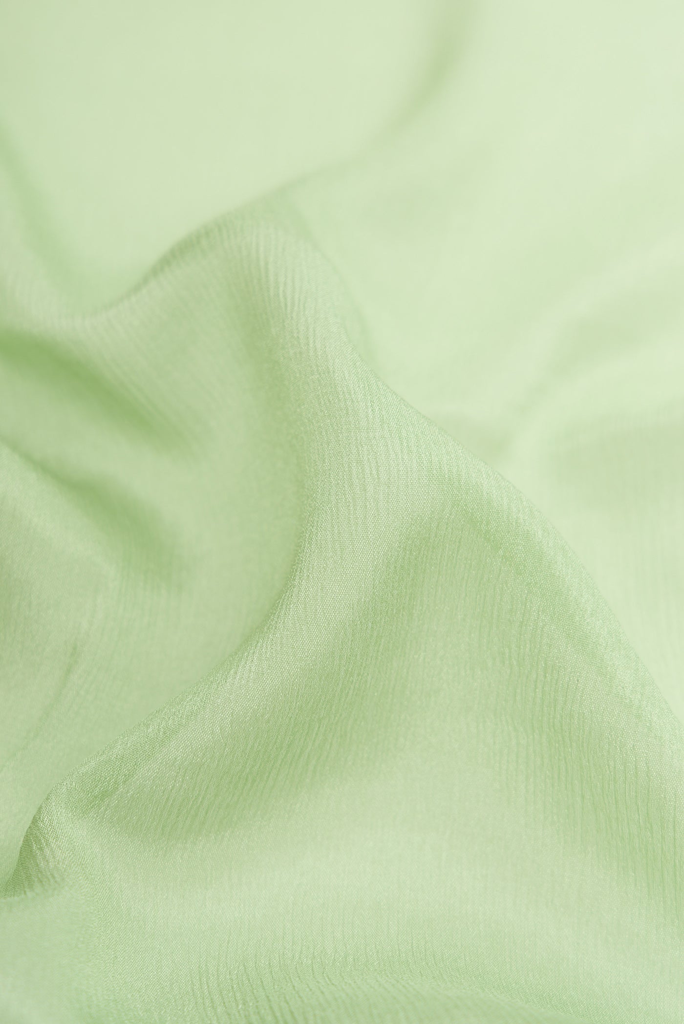 Close up of Pista Green Mysore Chiffon Saree with Plain Body and Zari Border.  displaying folds