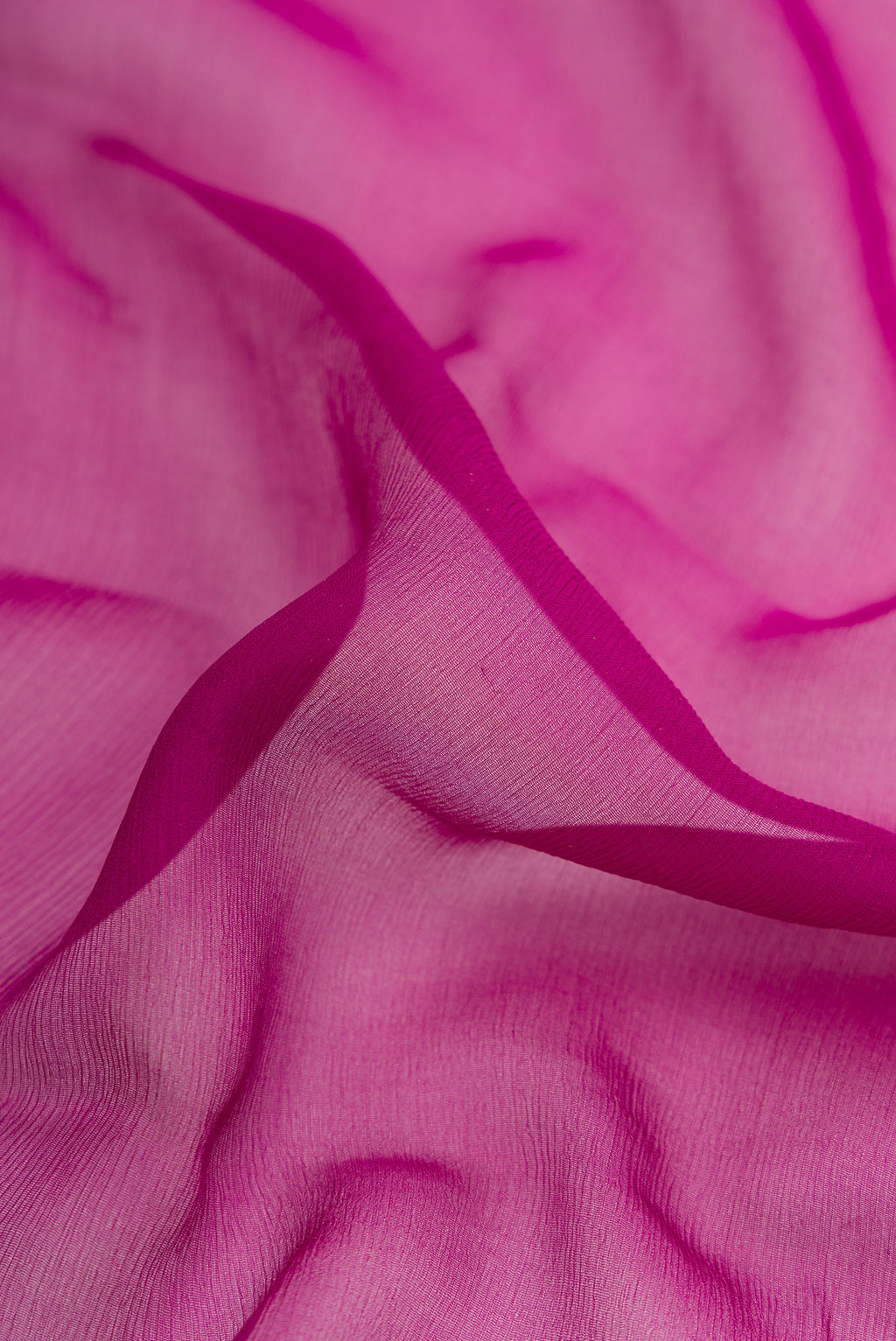 Close up of Magenta Dual Tone Mysore Georgette Saree with Plain Body and Zari Border.  displaying folds