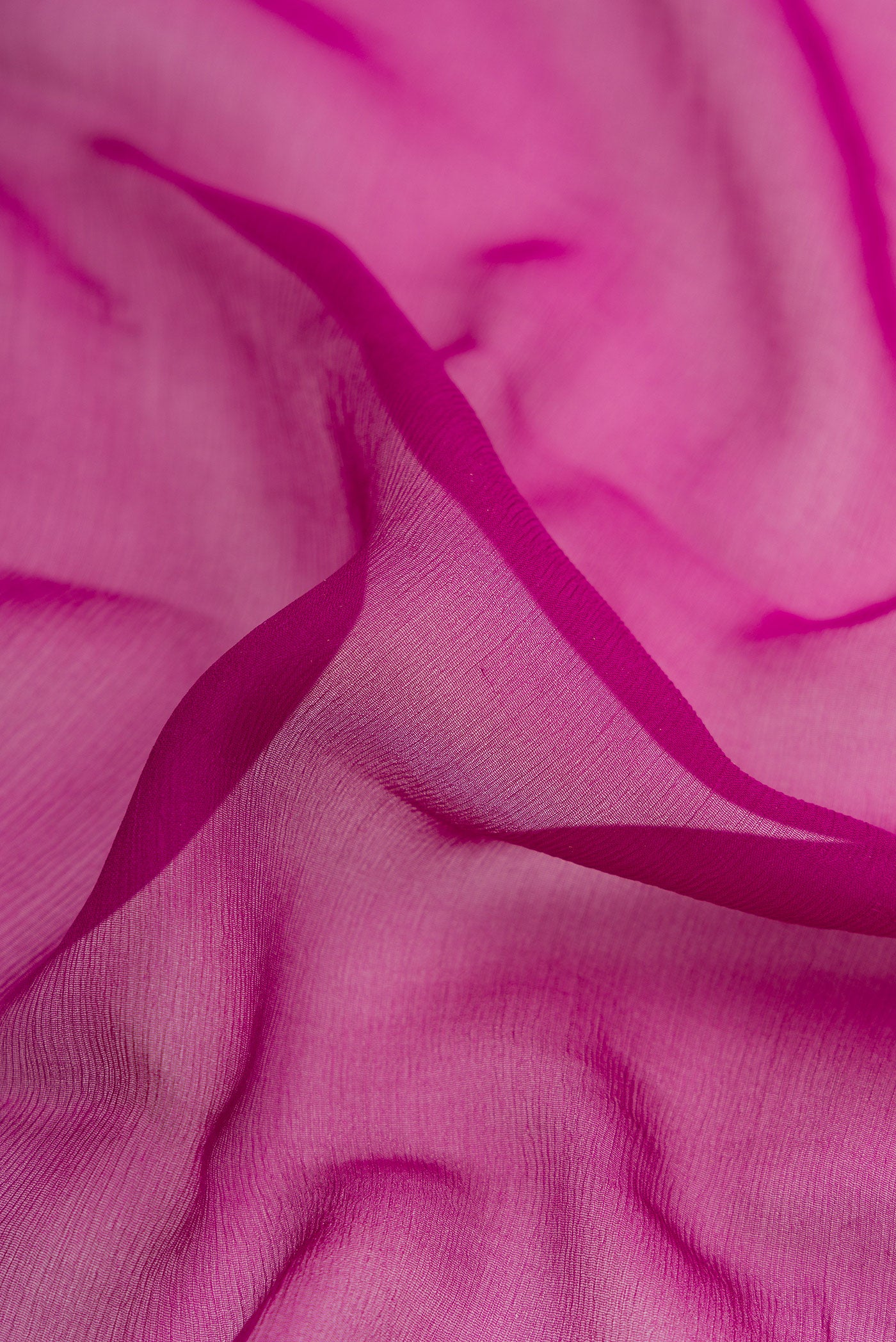 Close up of Magenta Dual Tone Mysore Georgette Saree with Plain Body and Zari Border.  displaying folds