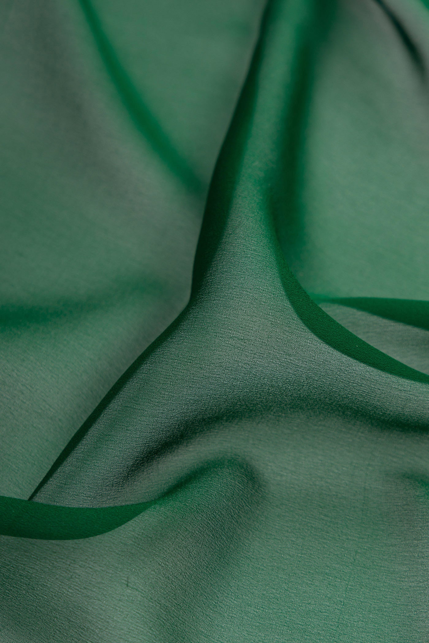 Close up of Bottle Green Mysore Georgette Saree with Plain Body and Zari Border.  displaying folds