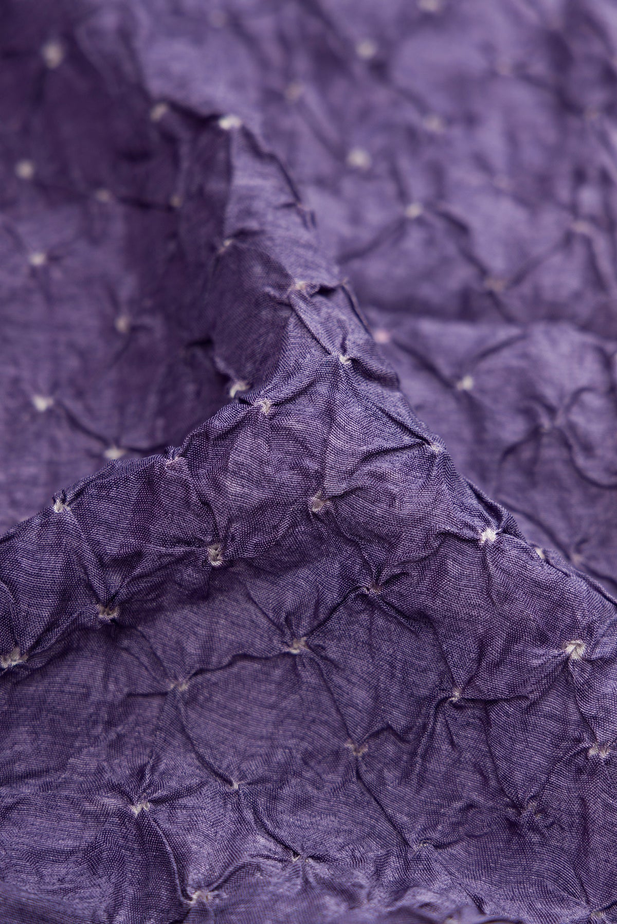 Close up of Lavender Blended Bandhani Silk Saree with Bandhani Print on the body and Zari Border.  displaying folds