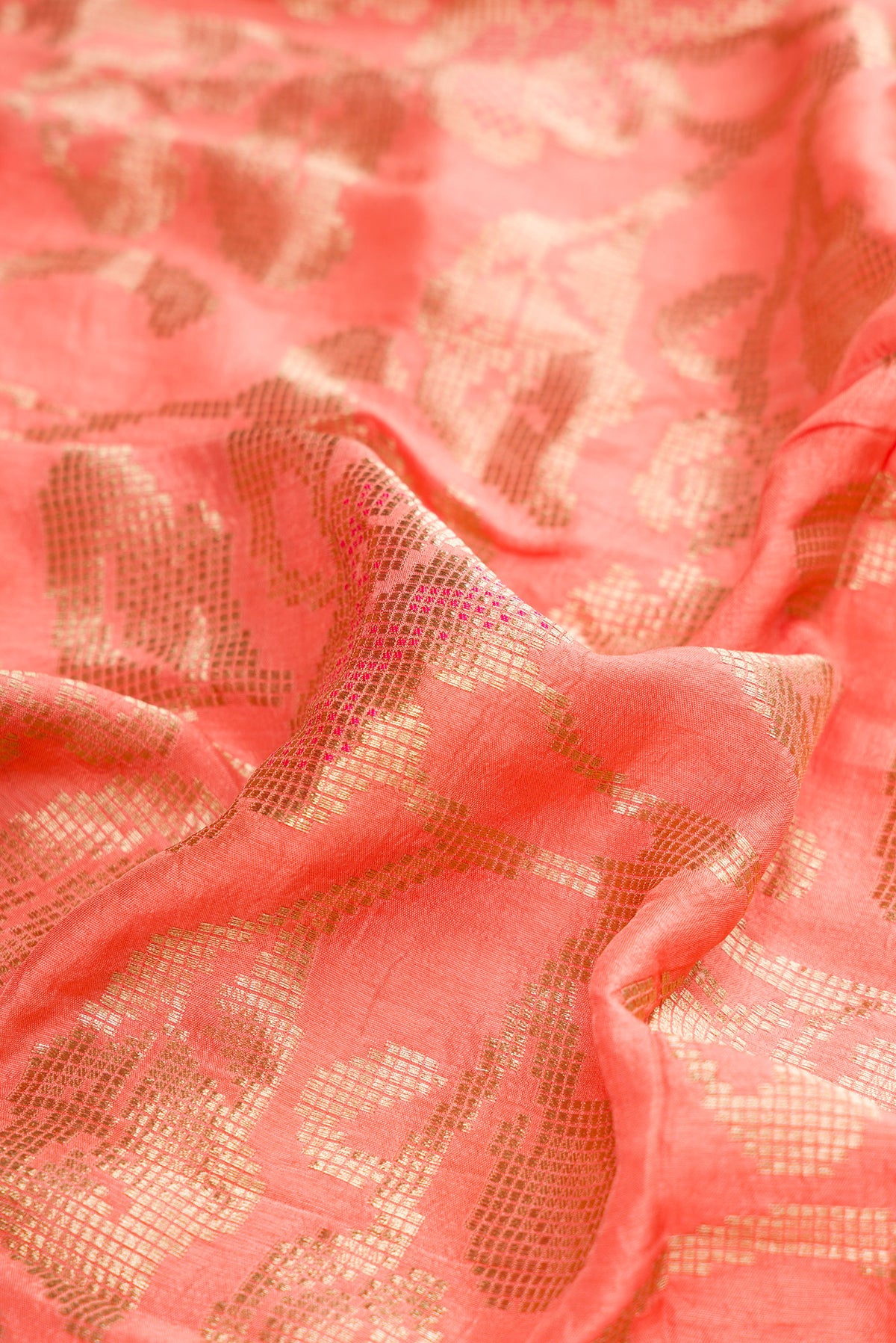 Close up of Peach Dual Tone Blended Bandhani Silk Saree with Zari Brocade on the body and Fancy Border.  displaying folds