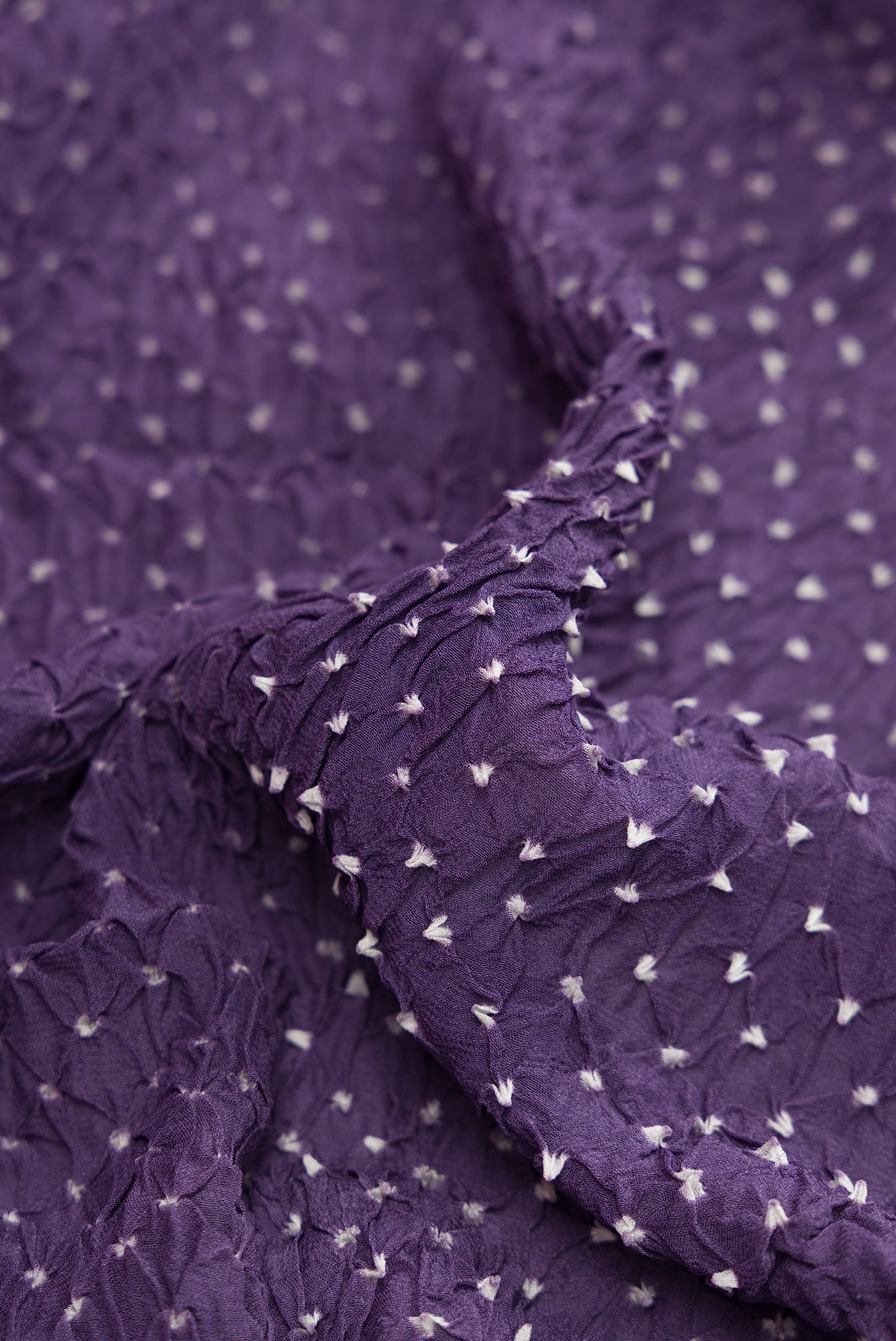 Close up of Lavender Bandhani Silk Saree with Bandhani Print on the body and Zari Border.  displaying folds