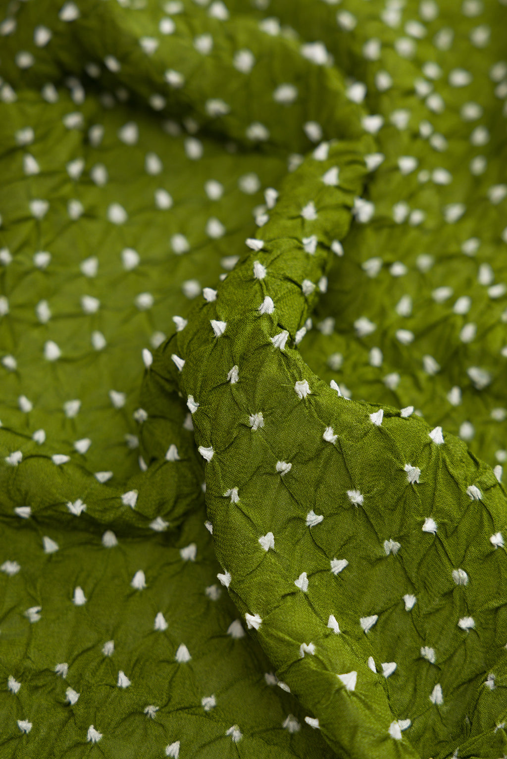 Close up of Mehandi Green Dual Tone Bandhani Silk Saree with Bandhani Print on the body and Zari Border.  displaying folds