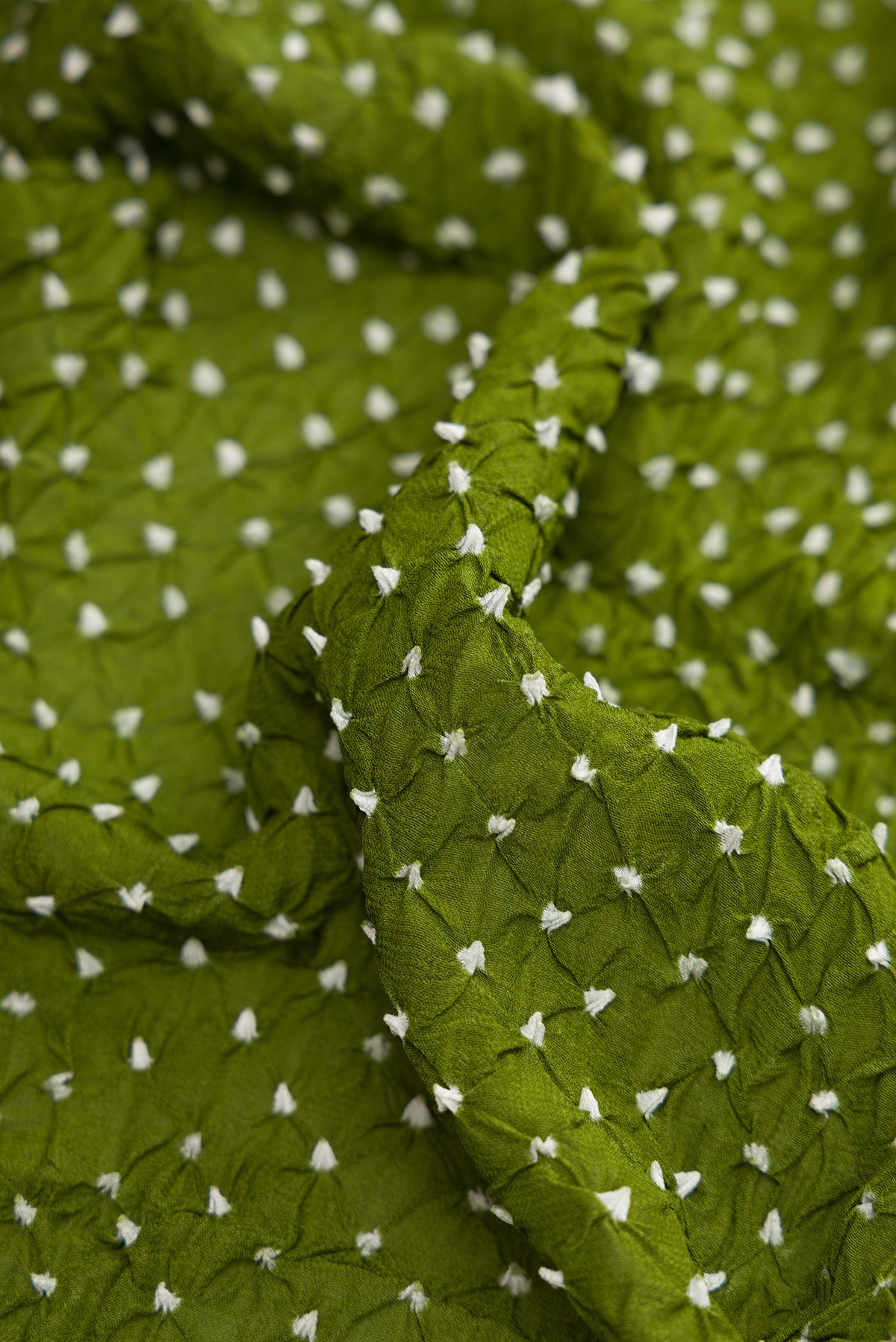 Close up of Mehandi Green Dual Tone Bandhani Silk Saree with Bandhani Print on the body and Zari Border.  displaying folds