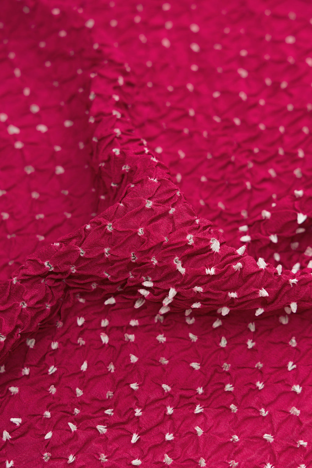 Close up of Magenta Dual Tone Bandhani Silk Saree with Bandhani Print on the body and Zari Border.  displaying folds