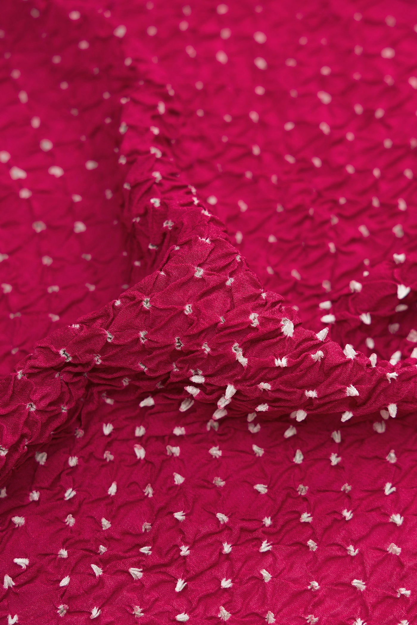 Close up of Magenta Dual Tone Bandhani Silk Saree with Bandhani Print on the body and Zari Border.  displaying folds