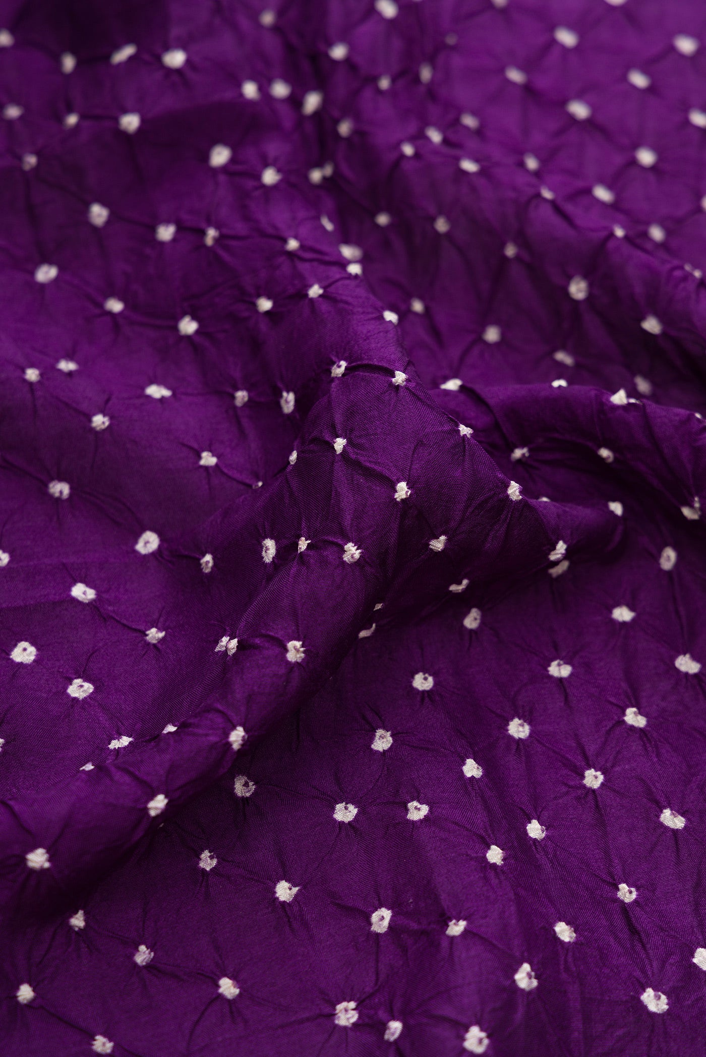 Close up of Violet Dual Tone Bandhani Silk Saree with Bandhani Print on the body and Paithani Border.  displaying folds