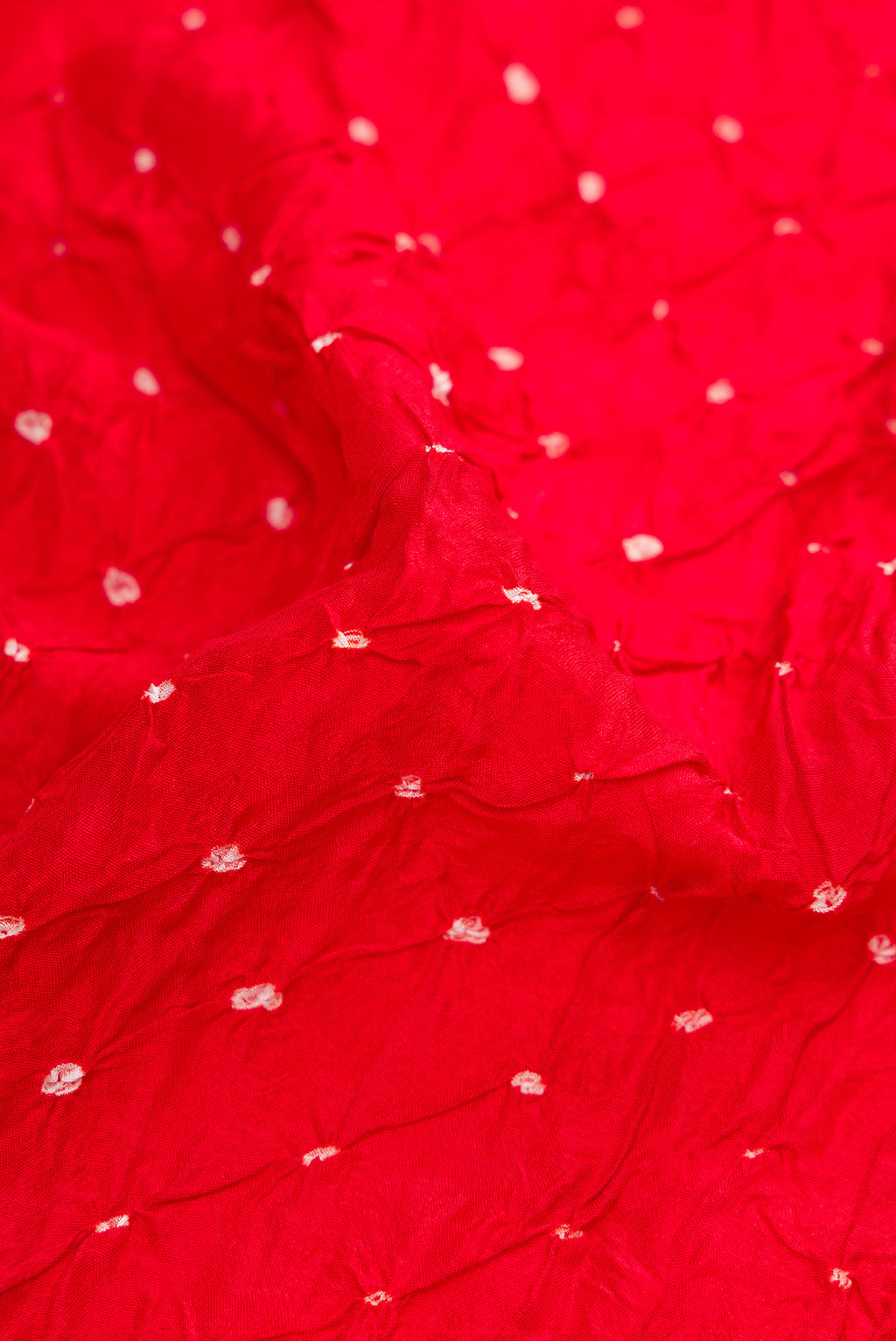 Close up of Red Bandhani Silk Saree with Bandhani Print on the body and Zari Border.  displaying folds