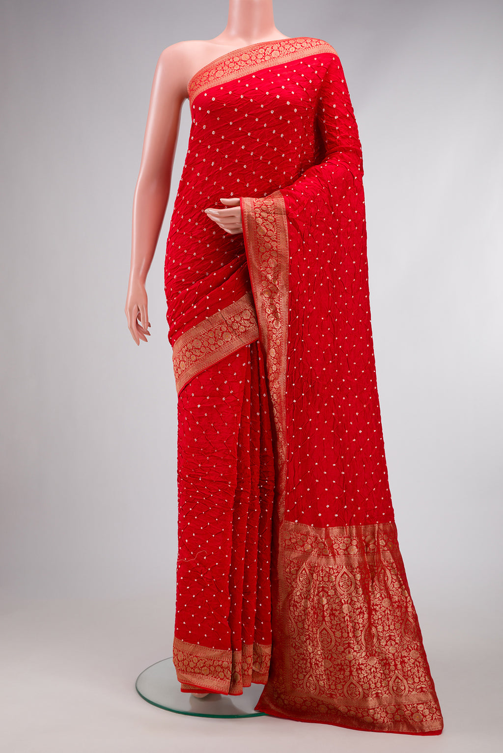 Red Bandhani Silk Saree with Bandhani Print on the body and Zari Border.  displayed on a mannequin