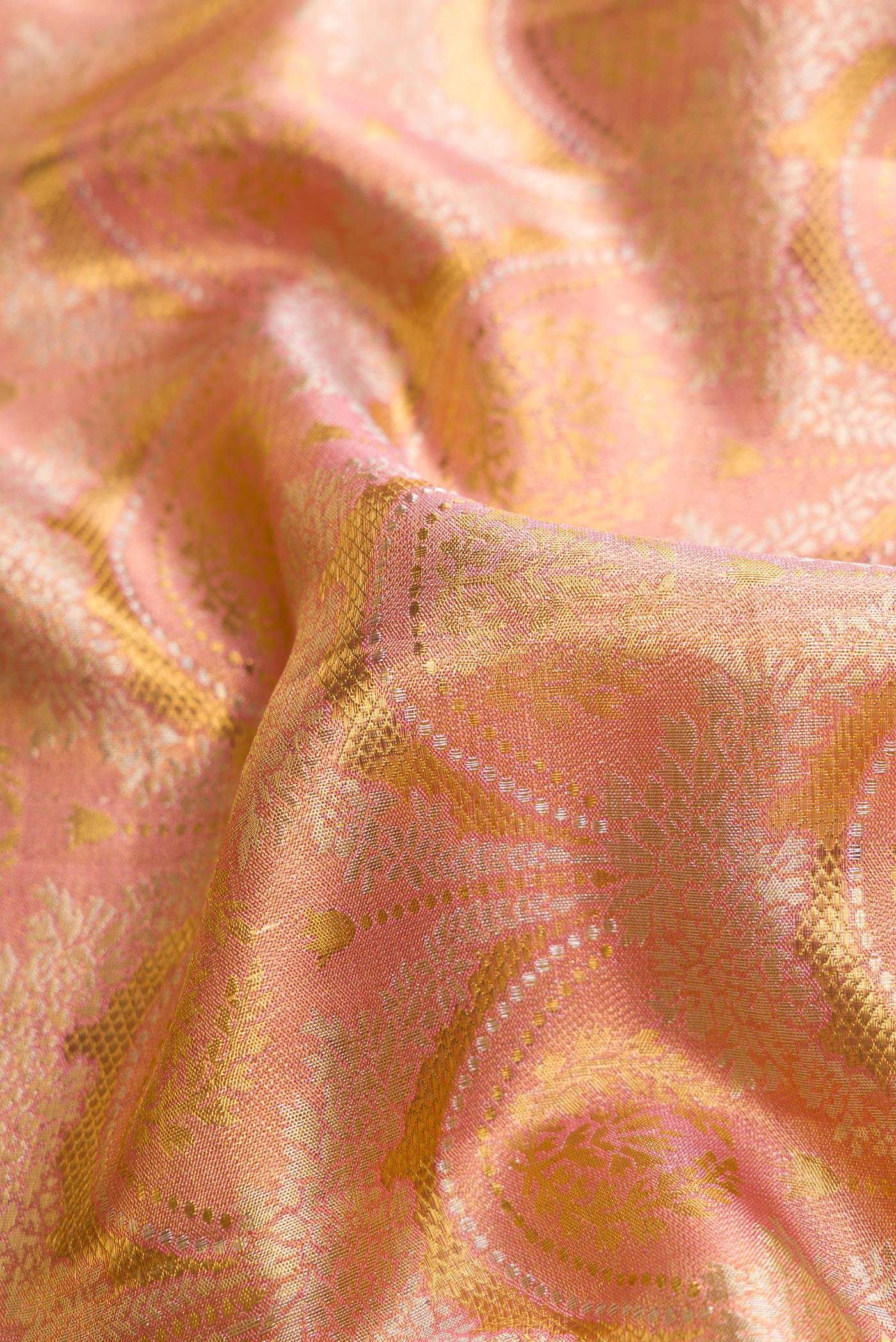 Close up of Rose Gold Dual Tone Kanjivaram Tissue Silk Saree with Zari Brocade on the body and Zari Border.  displaying folds